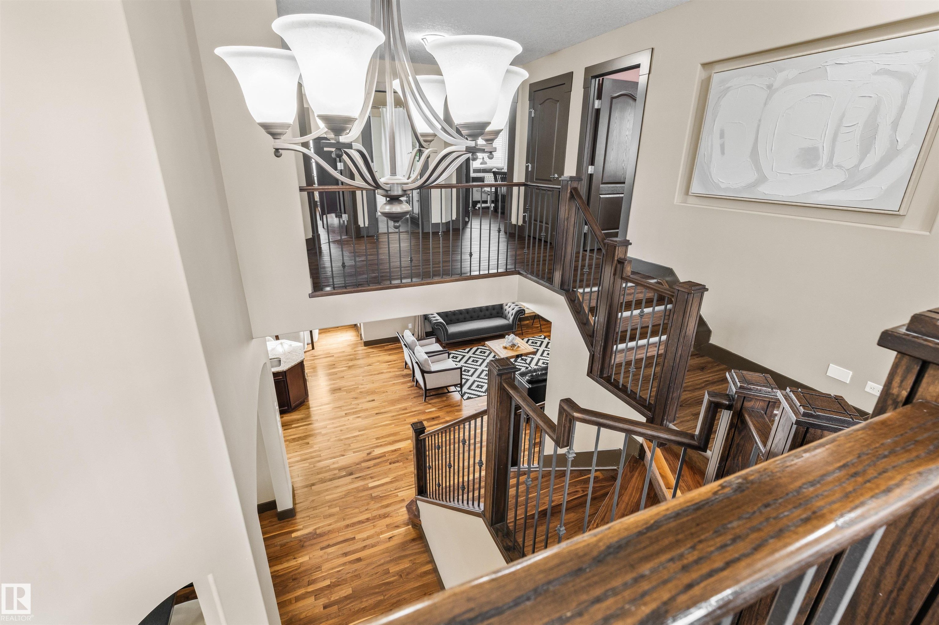 This property features a grand staircase with dark wood newel posts and railings, complemented by hardwood flooring throughout the visible areas - 1014 Hope Road, Edmonton, AB - Indoor Photo Showing Other Room