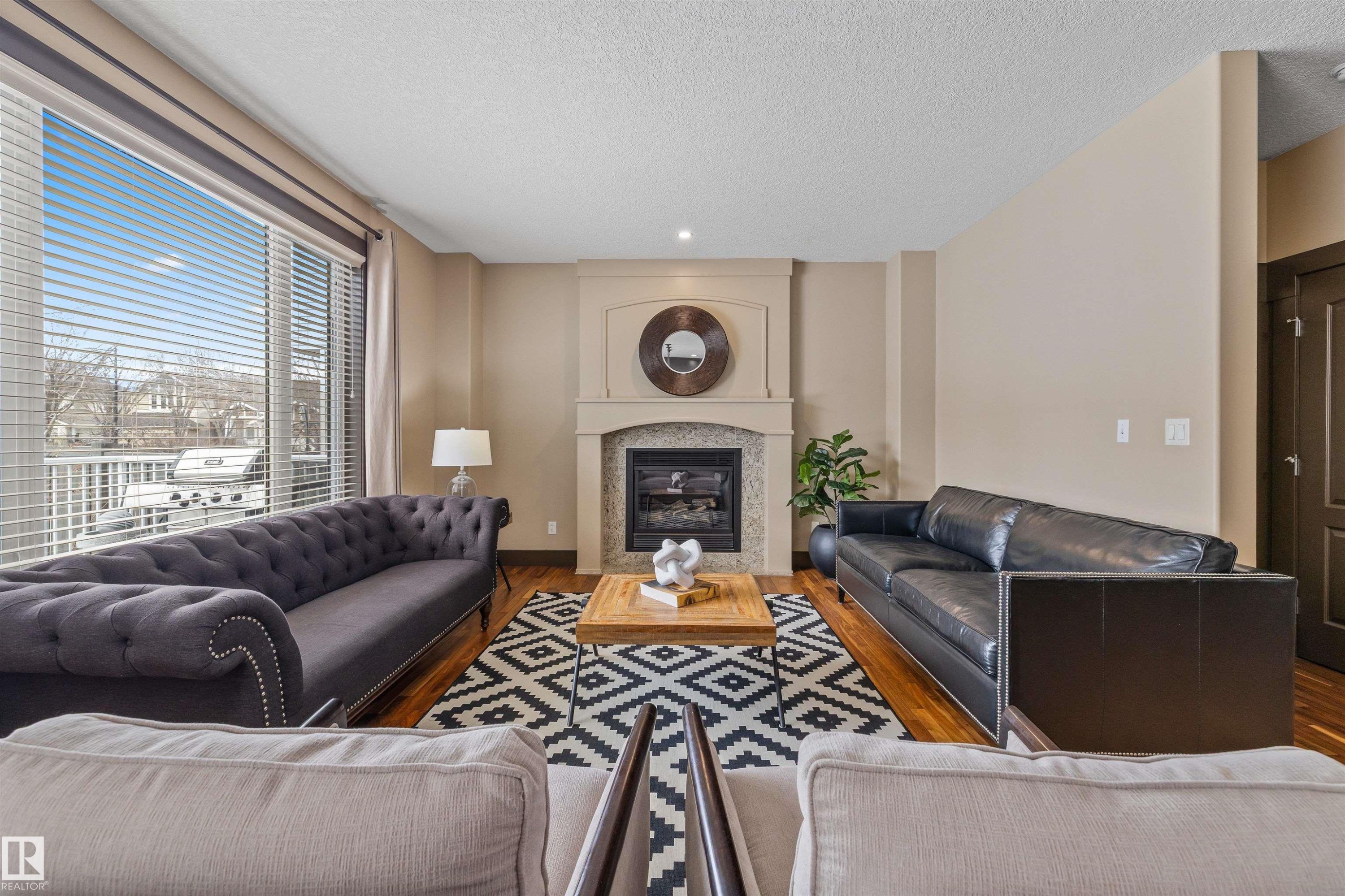 Bright living area with hardwood floors, a stone fireplace, and large sliding glass doors - 1014 Hope Road, Edmonton, AB - Indoor Photo Showing Living Room With Fireplace