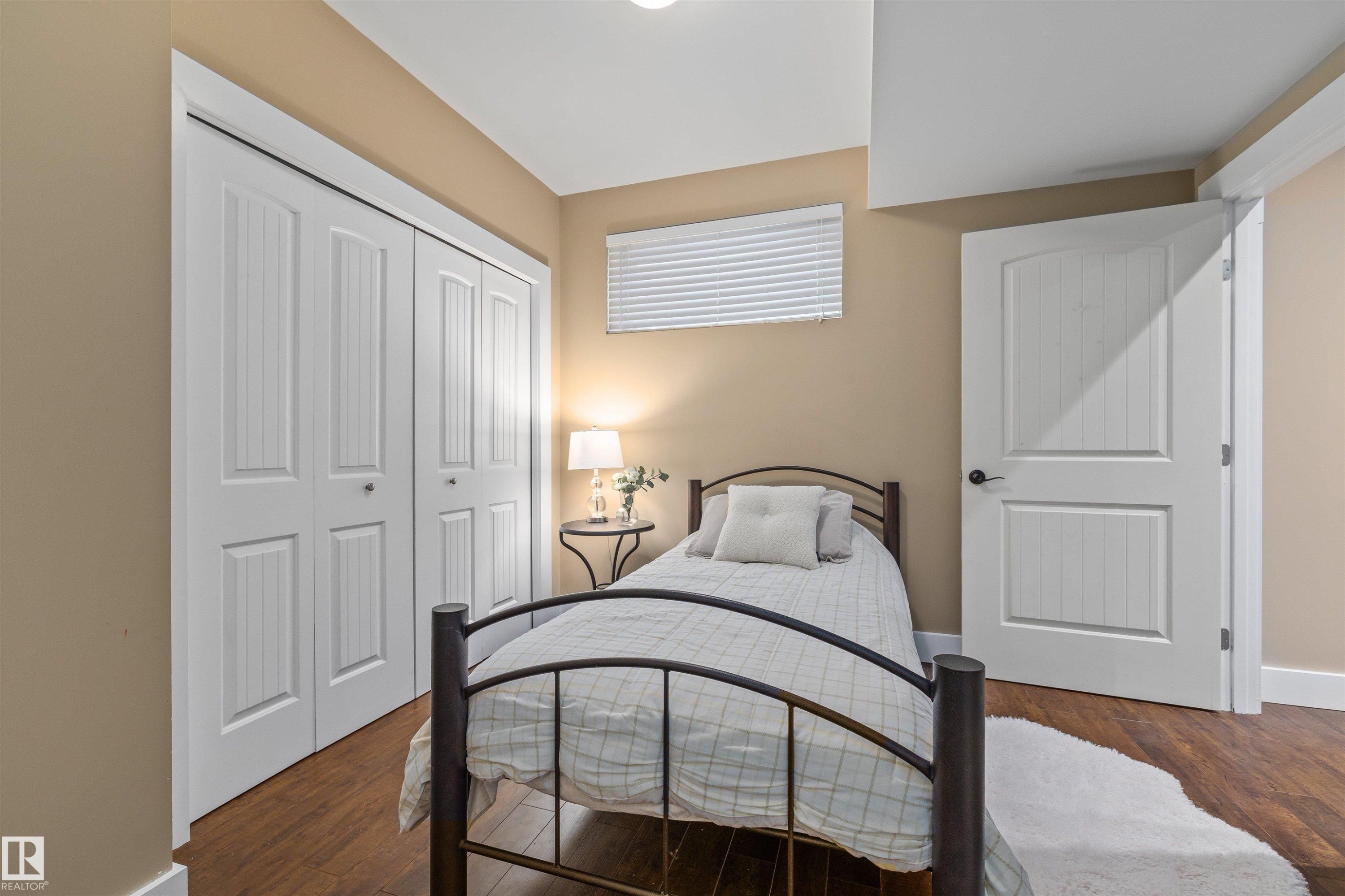This room features hardwood flooring, white paneled doors, and a neutral wall color - 1014 Hope Road, Edmonton, AB - Indoor Photo Showing Bedroom