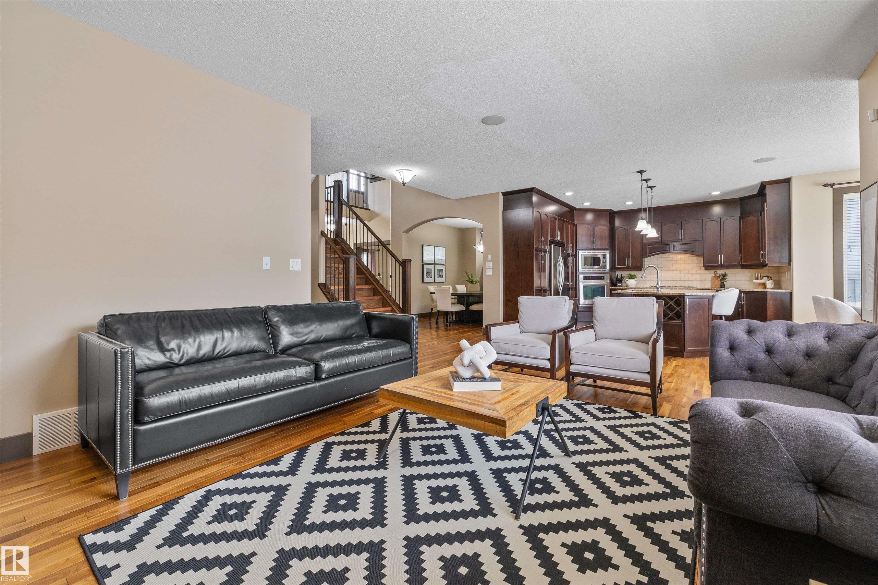 This spacious living area features hardwood floors and a view of the kitchen with dark wood cabinetry - 1014 Hope Road, Edmonton, AB - Indoor Photo Showing Living Room