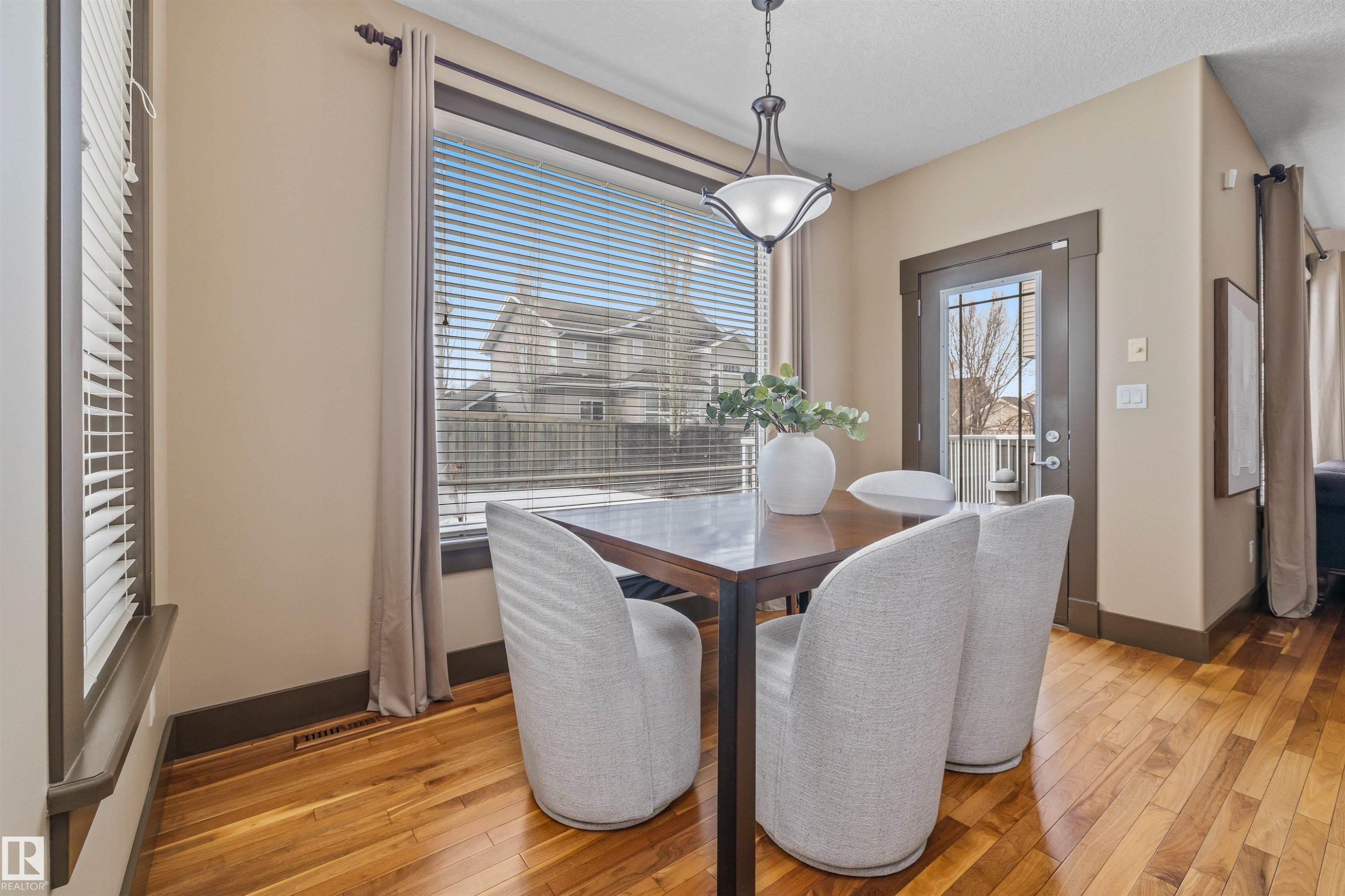 This dining area features hardwood flooring, a large window with blinds, and a glass-paneled door - 1014 Hope Road, Edmonton, AB - Indoor Photo Showing Dining Room