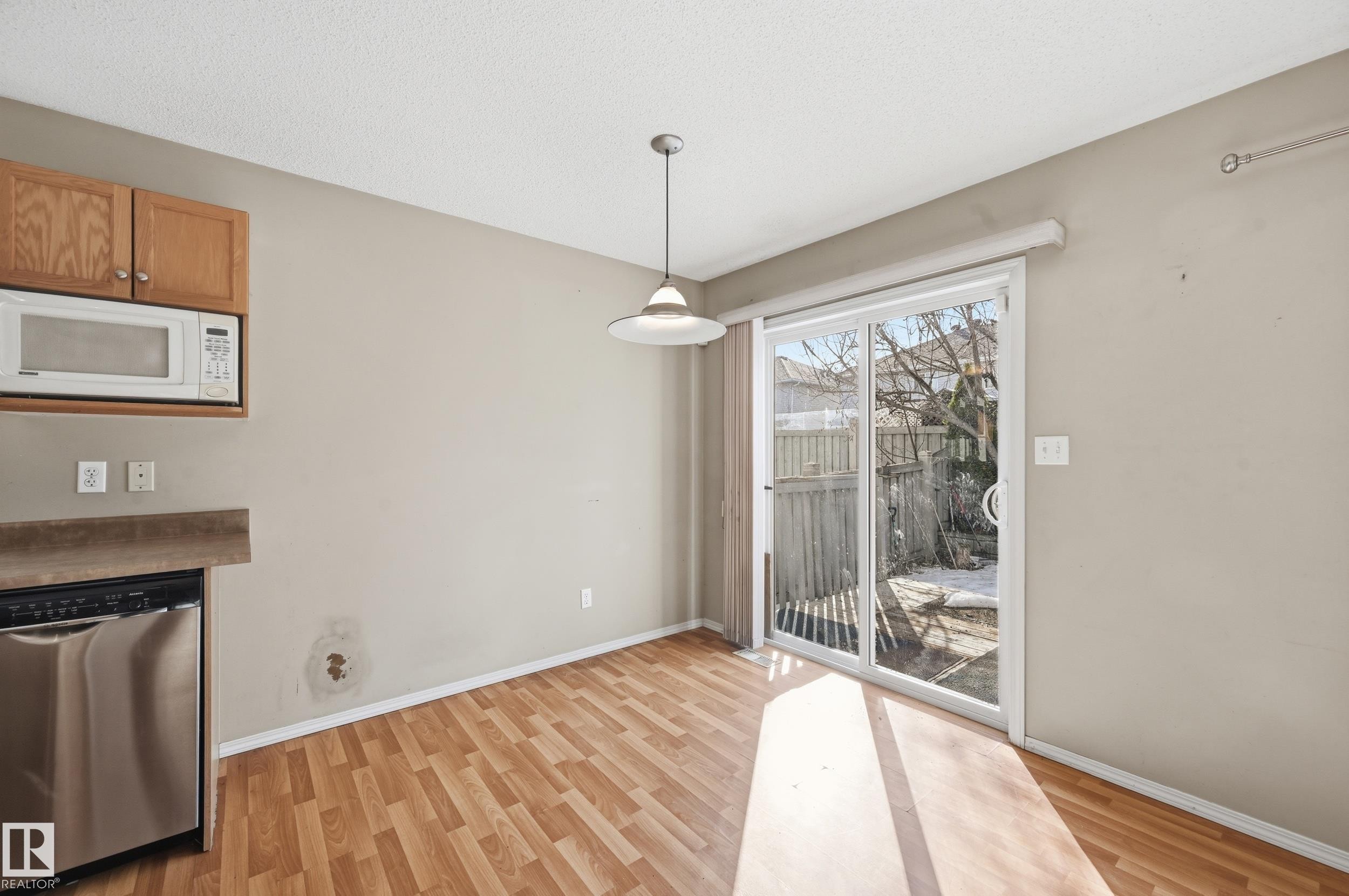 The eat-in kitchen features wood-look flooring, light wood cabinetry, and a sliding glass door providing natural light and access to the outdoors - 53 287 Macewan Road, Edmonton, AB - Indoor With Fireplace
