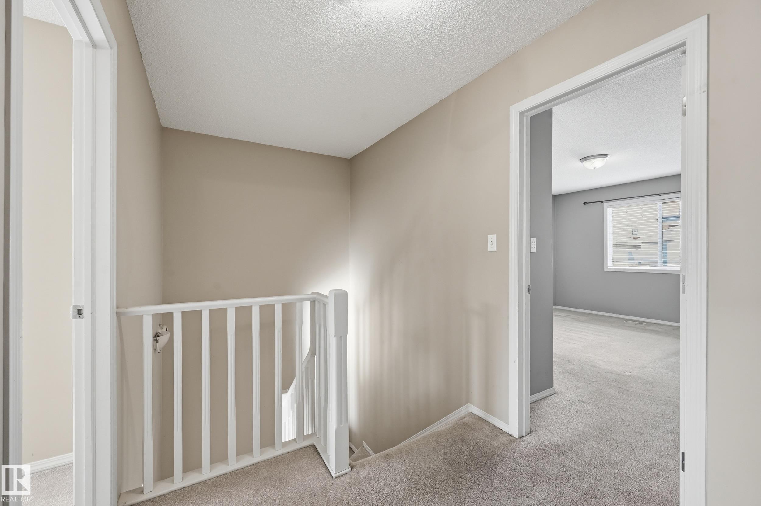 A well-lit hallway with neutral wall colors and carpeted flooring - 53 287 Macewan Road, Edmonton, AB - Indoor Photo Showing Other Room