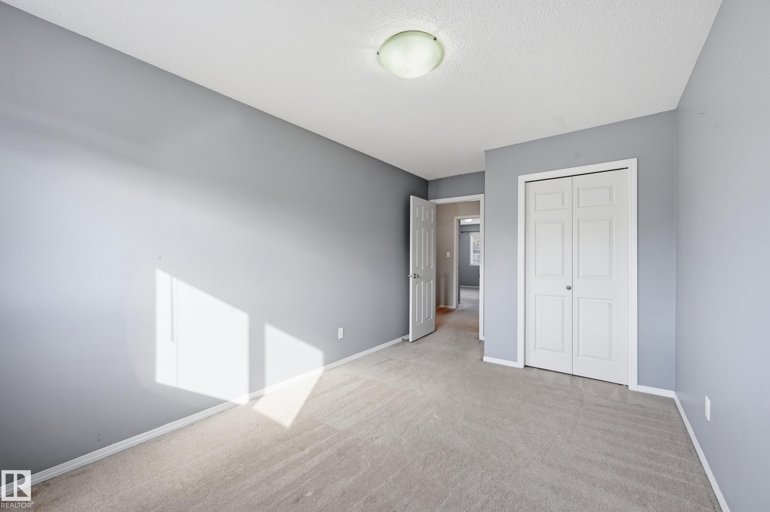 This room features light grey walls, carpeted flooring, and a ceiling light fixture - 53 287 Macewan Road, Edmonton, AB - Indoor Photo Showing Other Room