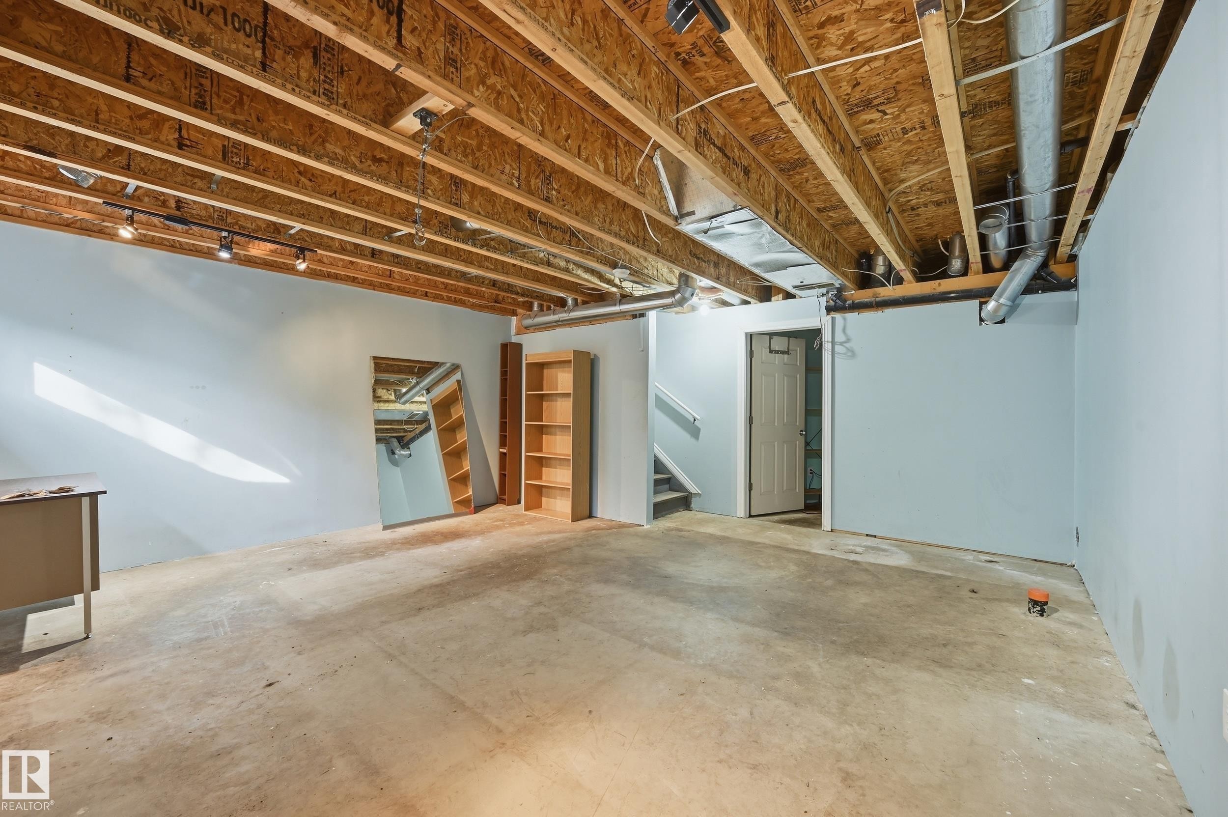This spacious lower level features light blue painted walls, exposed ceiling joists, and concrete flooring - 53 287 Macewan Road, Edmonton, AB - Indoor Photo Showing Basement