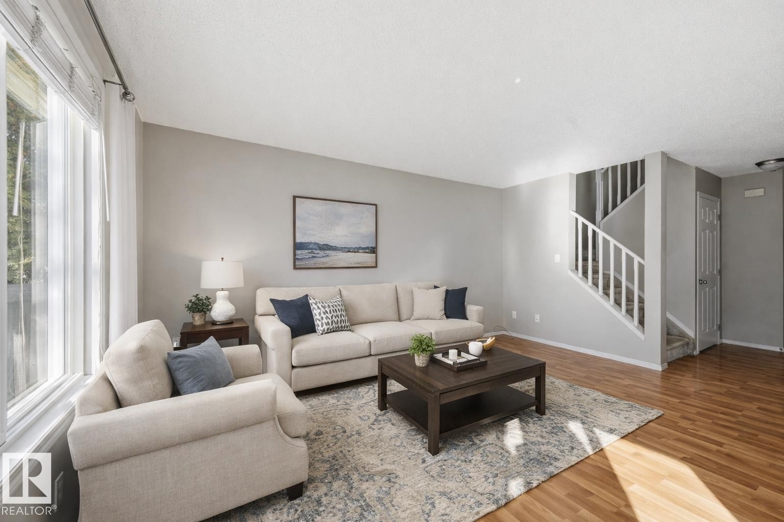 This living area features light-toned walls, hardwood floors, and a prominent window providing natural light - 53 287 Macewan Road, Edmonton, AB - Indoor Photo Showing Living Room