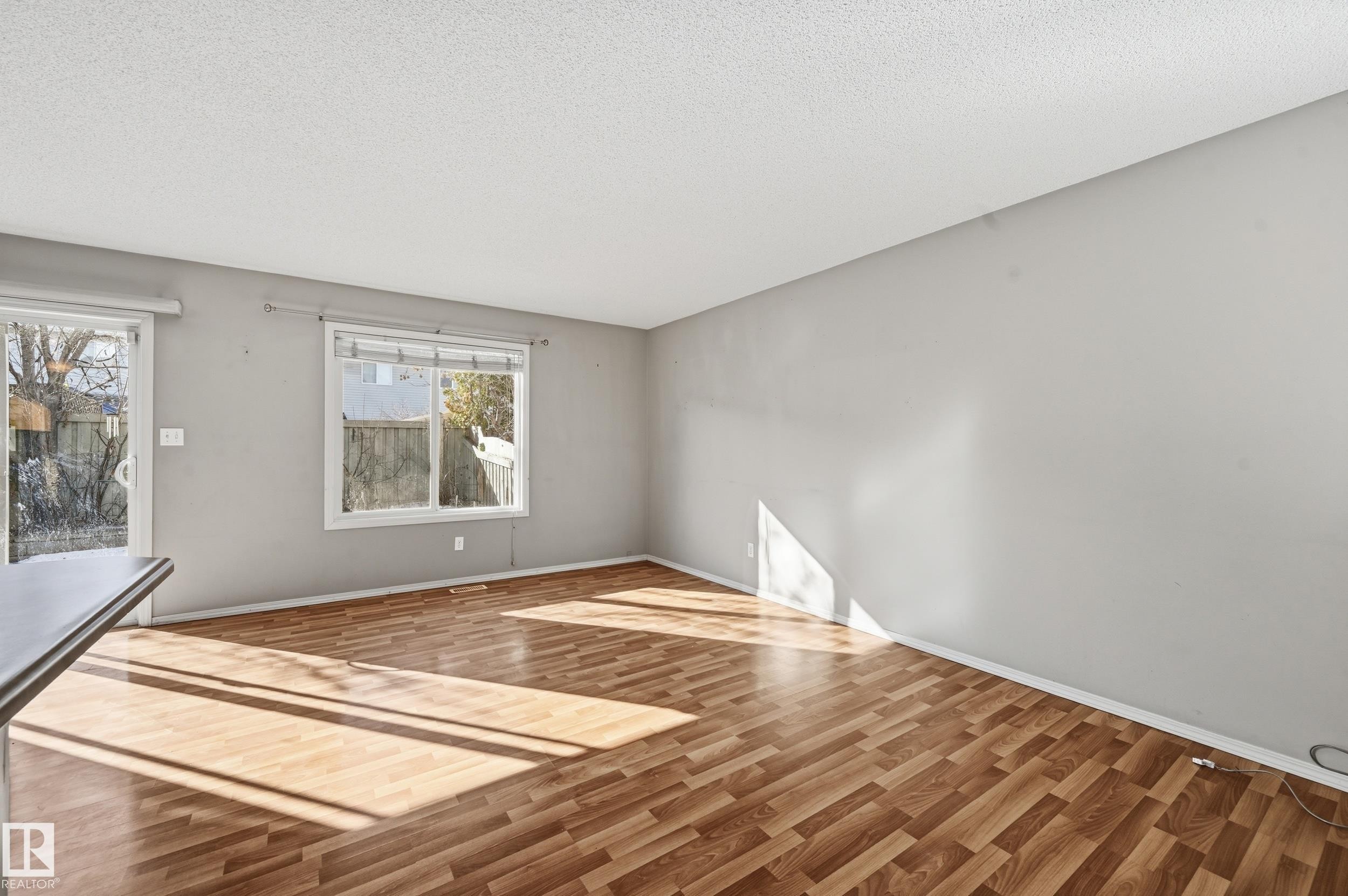 Living area featuring light wood flooring, a window providing natural light, and a sliding glass door - 53 287 Macewan Road, Edmonton, AB - Indoor Photo Showing Other Room
