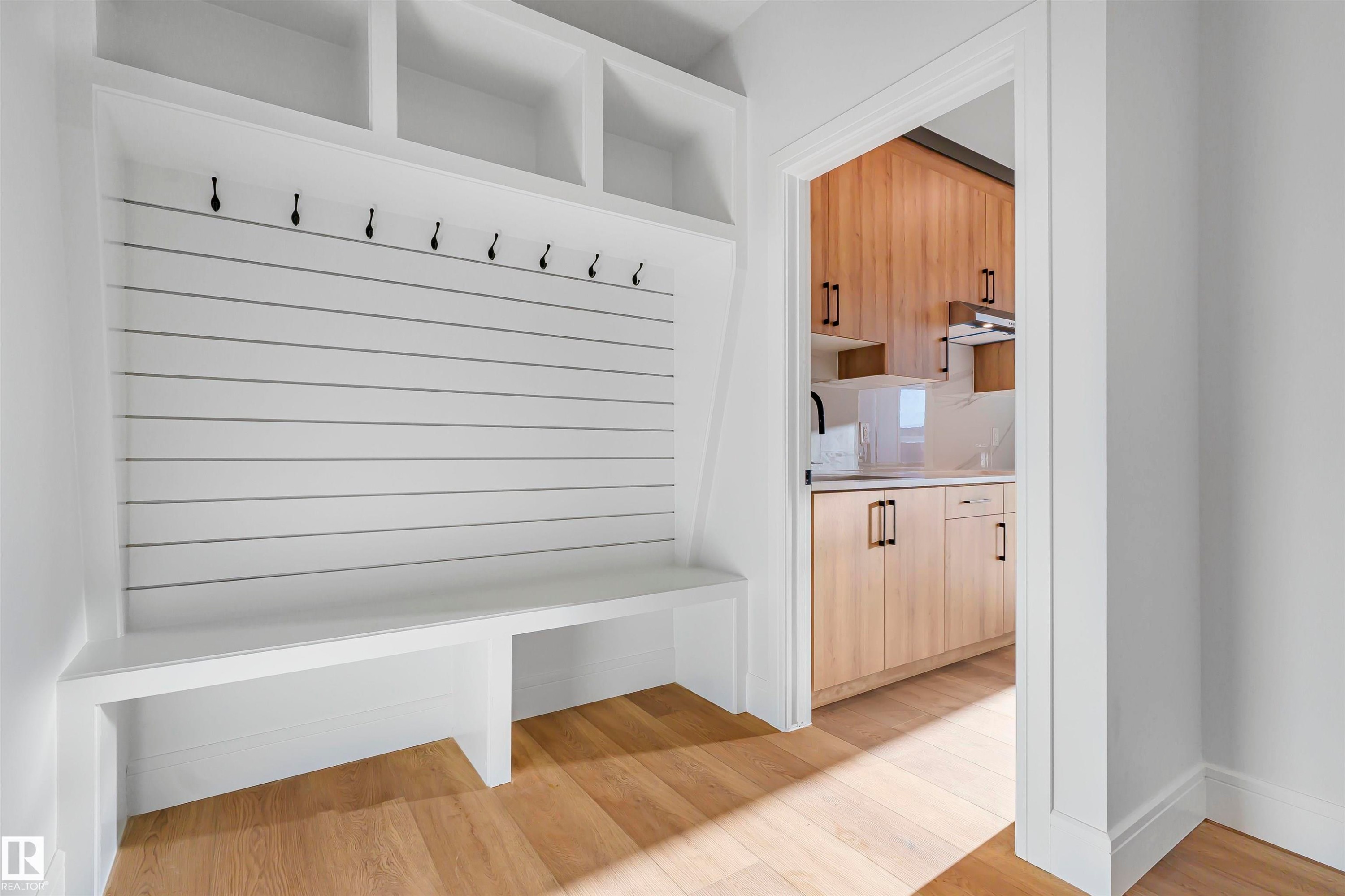 Entryway featuring a white built-in bench with storage cubbies and coat hooks, with light wood flooring - 368 Creekside Green, Leduc, AB - Indoor