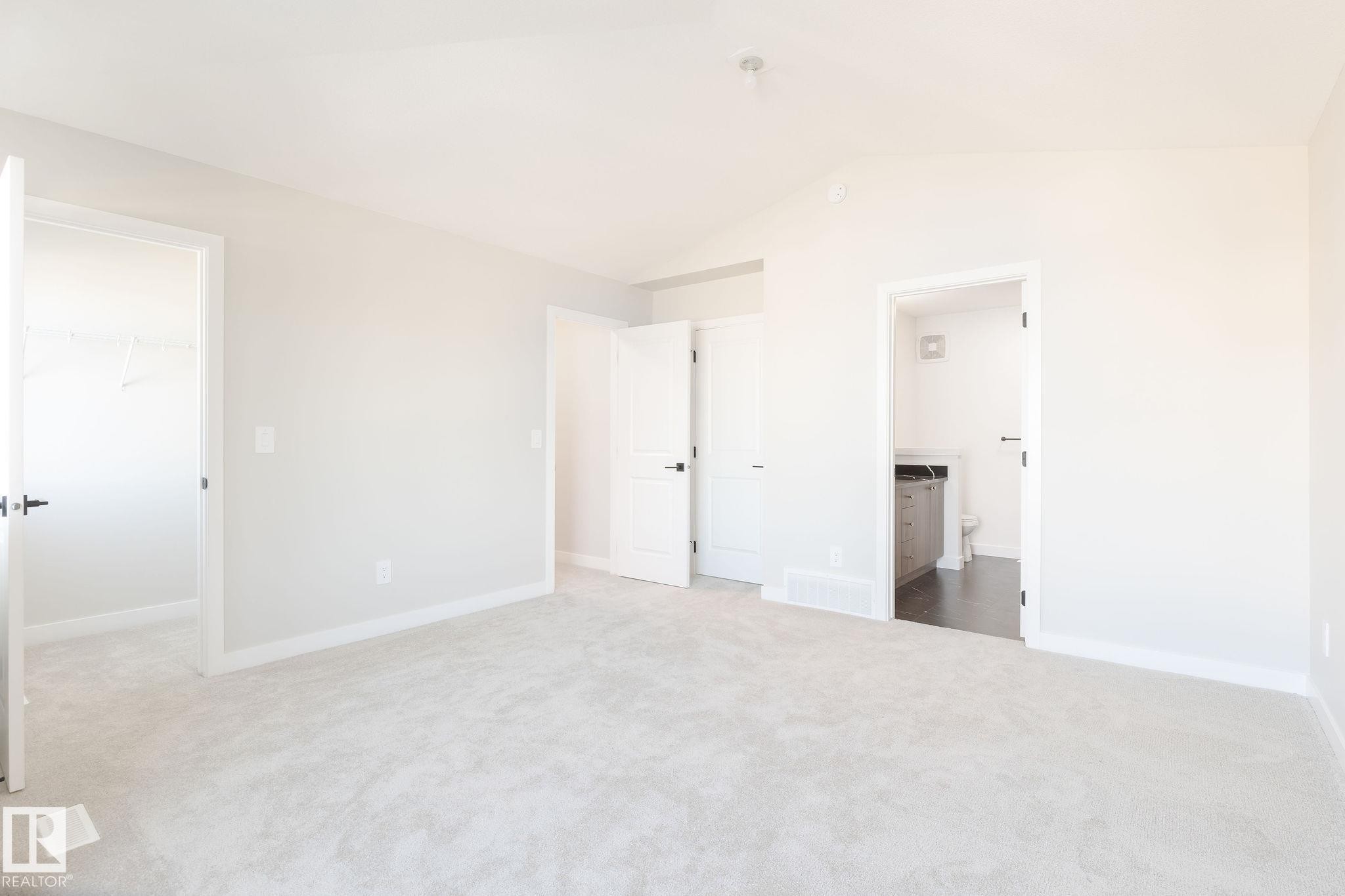 This bright room features light-colored carpeting, white walls, and a vaulted ceiling - 2206 Crossbill Link, Edmonton, AB - Indoor Photo Showing Other Room