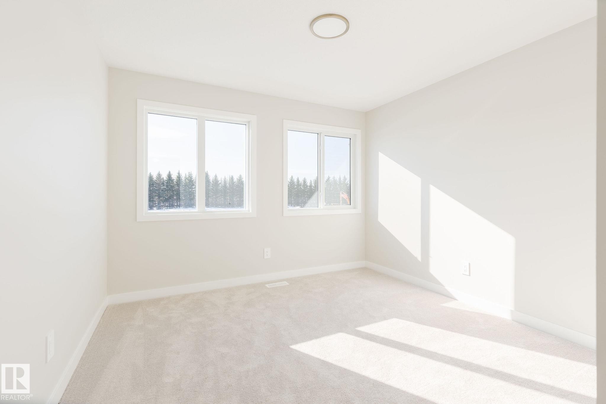 The room features two windows providing ample natural light, light-colored carpeted flooring, and a ceiling light fixture - 2206 Crossbill Link, Edmonton, AB - Indoor Photo Showing Other Room