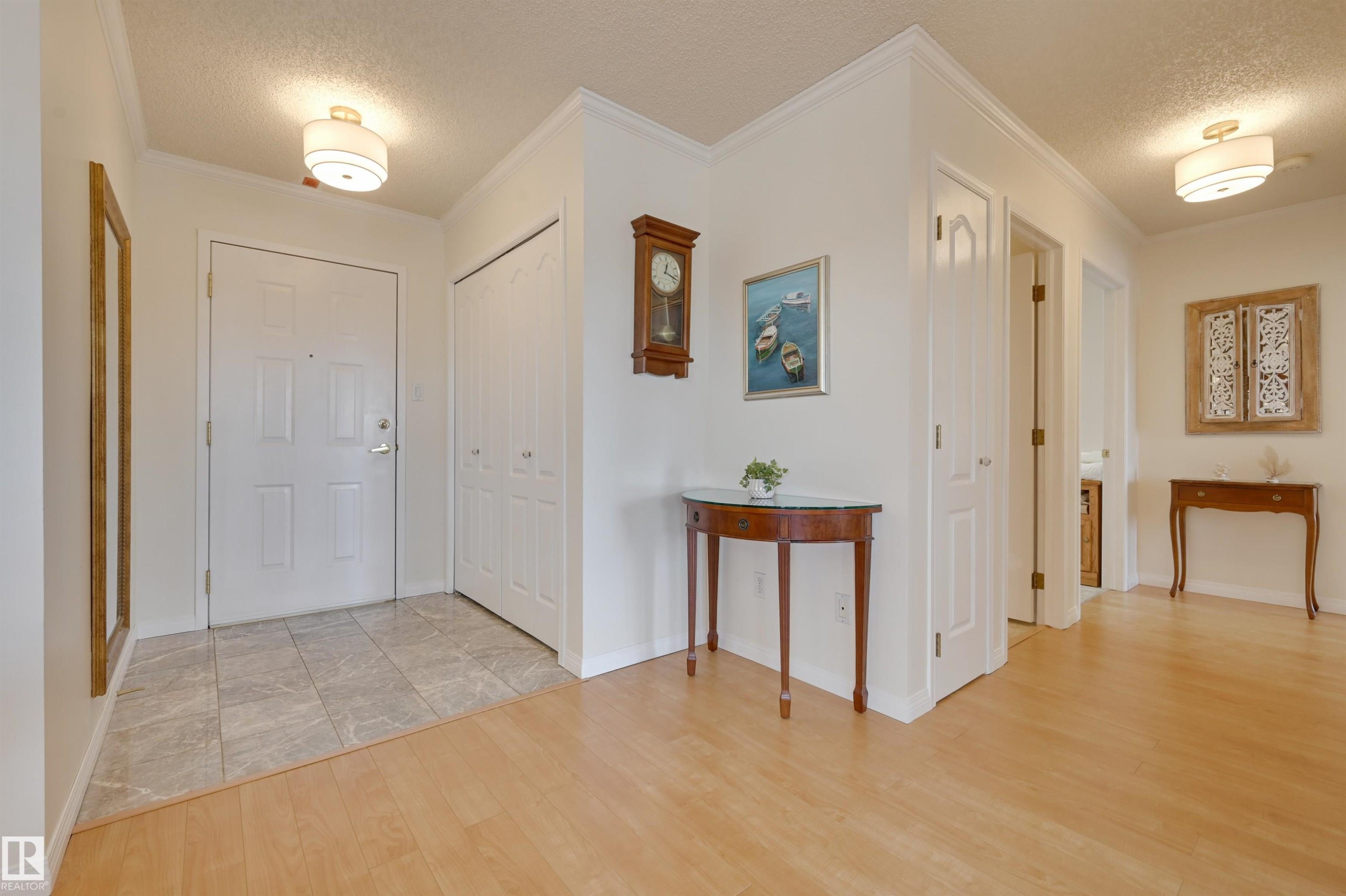 This inviting entryway features light-colored flooring, including both tile and wood, complemented by neutral wall tones - 304 17151 94A Avenue, Edmonton, AB - Indoor Photo Showing Other Room