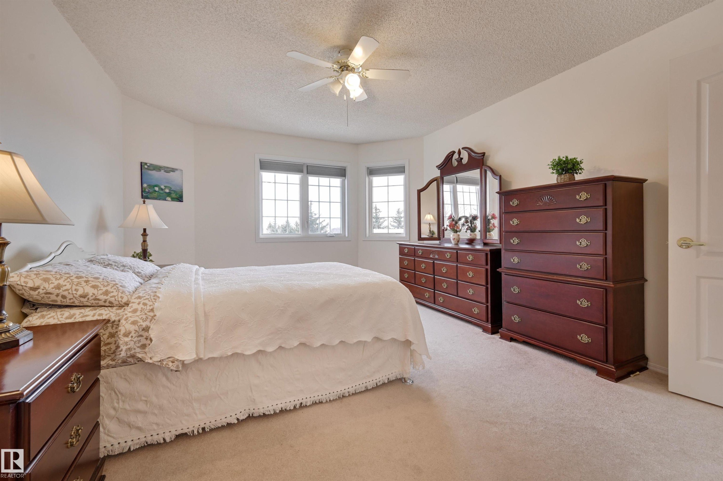 This room features light-colored carpeting, a ceiling fan, and windows with white frames - 304 17151 94A Avenue, Edmonton, AB - Indoor Photo Showing Bedroom