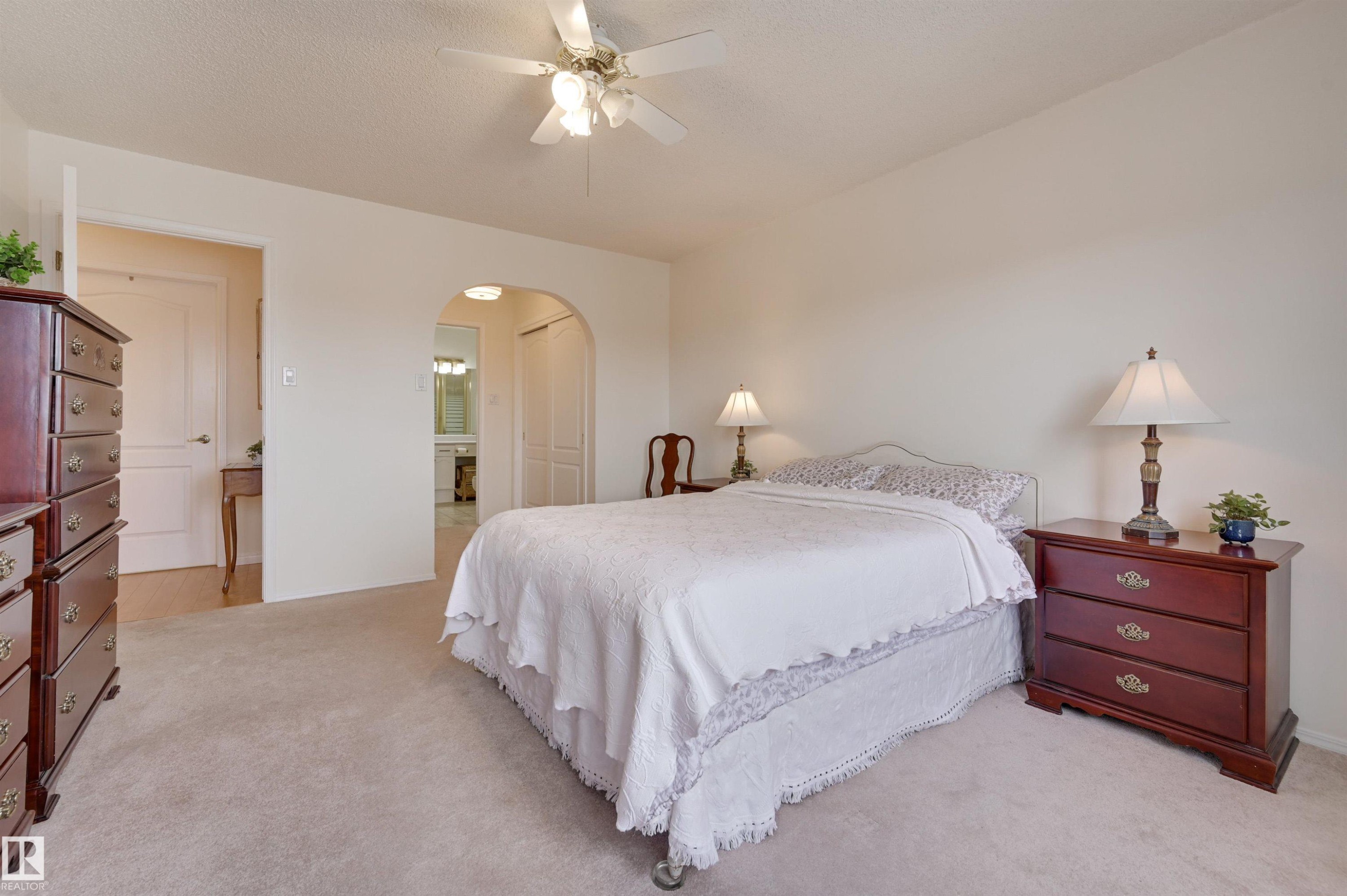 The property features a bright room with light-colored carpeting, a ceiling fan with integrated lighting, and an arched doorway - 304 17151 94A Avenue, Edmonton, AB - Indoor Photo Showing Bedroom