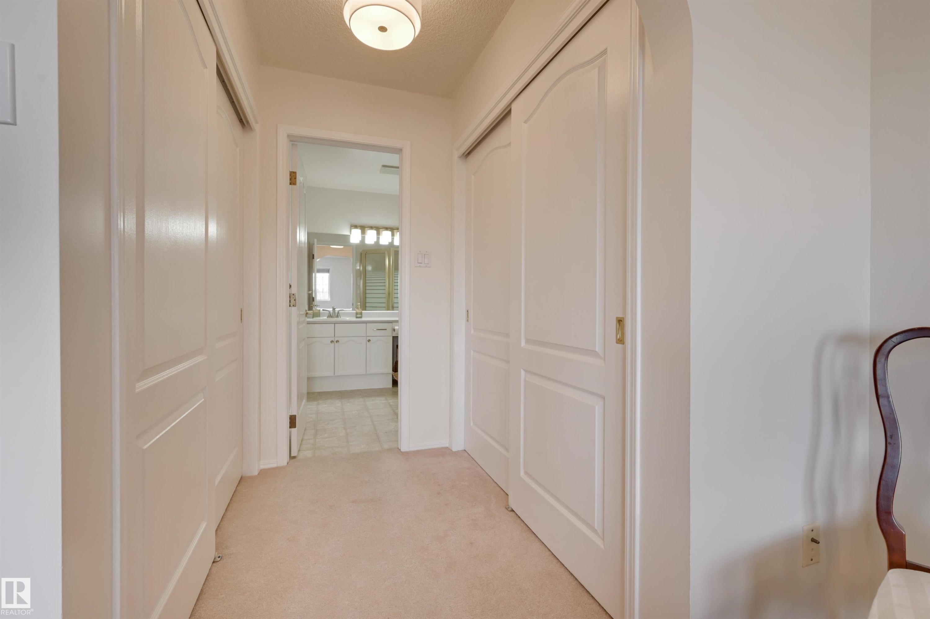 Hallway featuring light-colored carpet flooring and white closet doors - 304 17151 94A Avenue, Edmonton, AB - Indoor Photo Showing Other Room