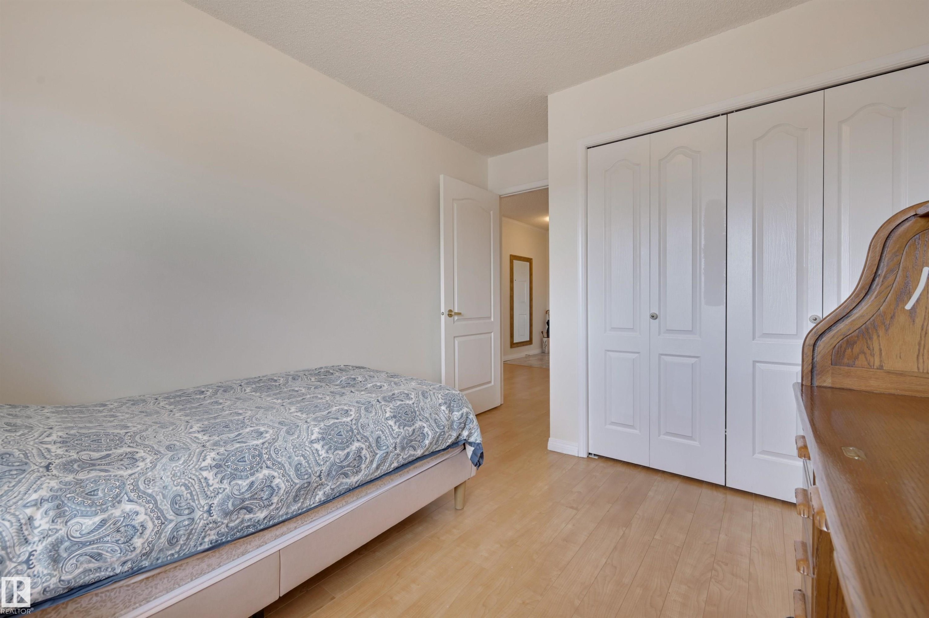 This room features light-colored walls and light wood flooring throughout, creating a bright and airy atmosphere - 304 17151 94A Avenue, Edmonton, AB - Indoor Photo Showing Bedroom