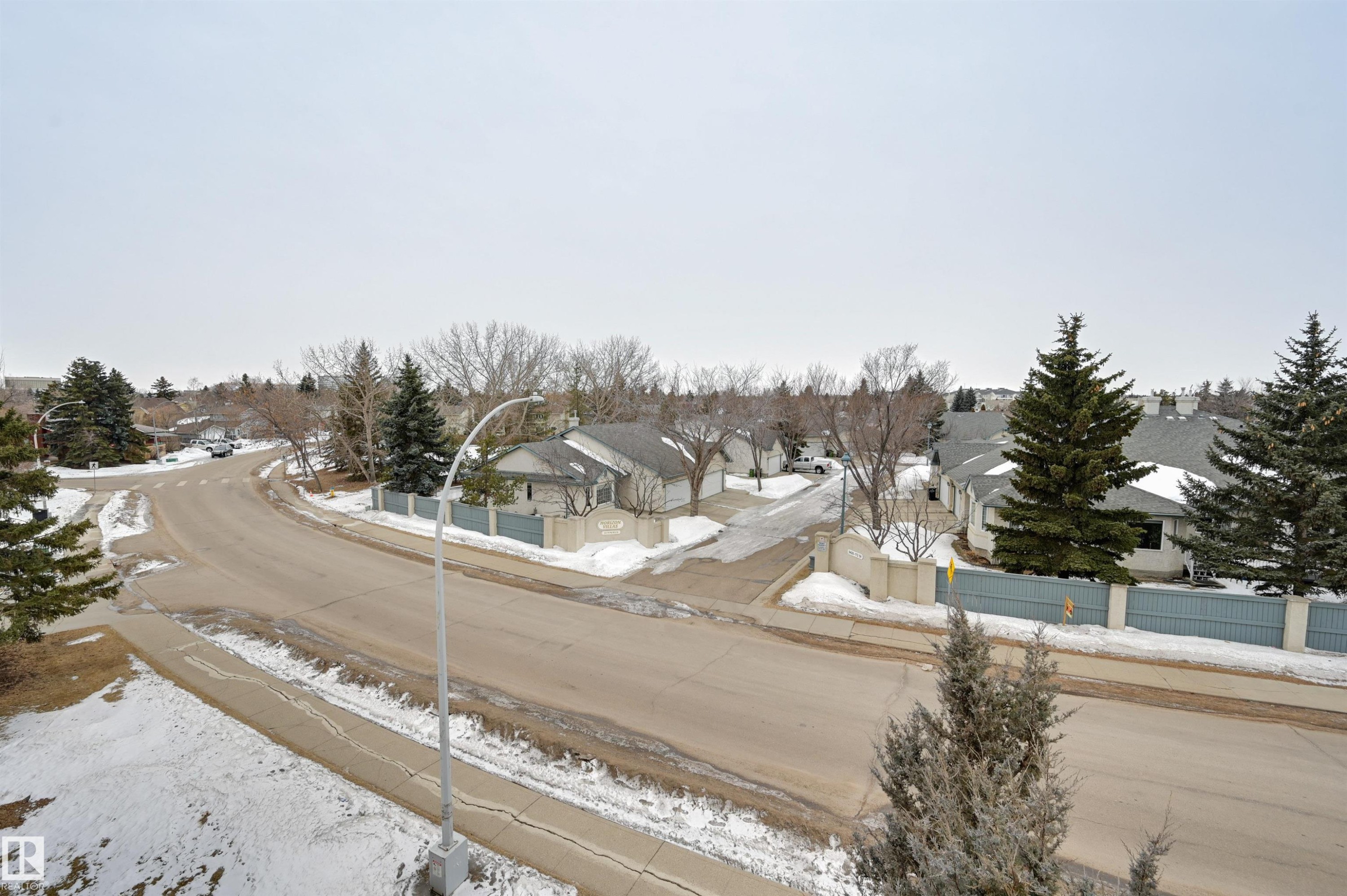 View of the neighborhood featuring paved roads, sidewalks, and surrounding properties with green trees - 304 17151 94A Avenue, Edmonton, AB - Outdoor With View