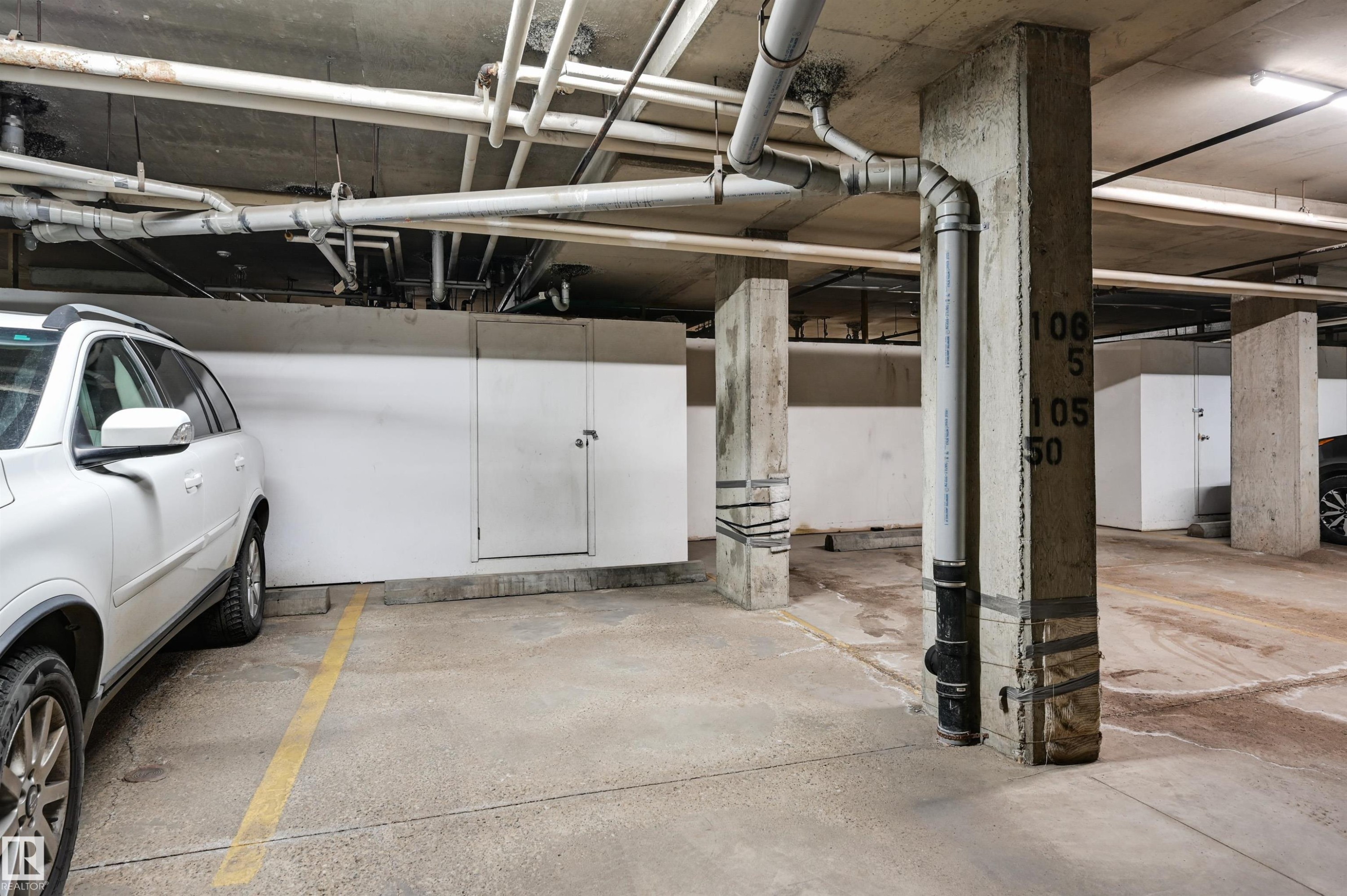 Designated parking space with a concrete floor and exposed overhead piping - 304 17151 94A Avenue, Edmonton, AB - Indoor Photo Showing Garage