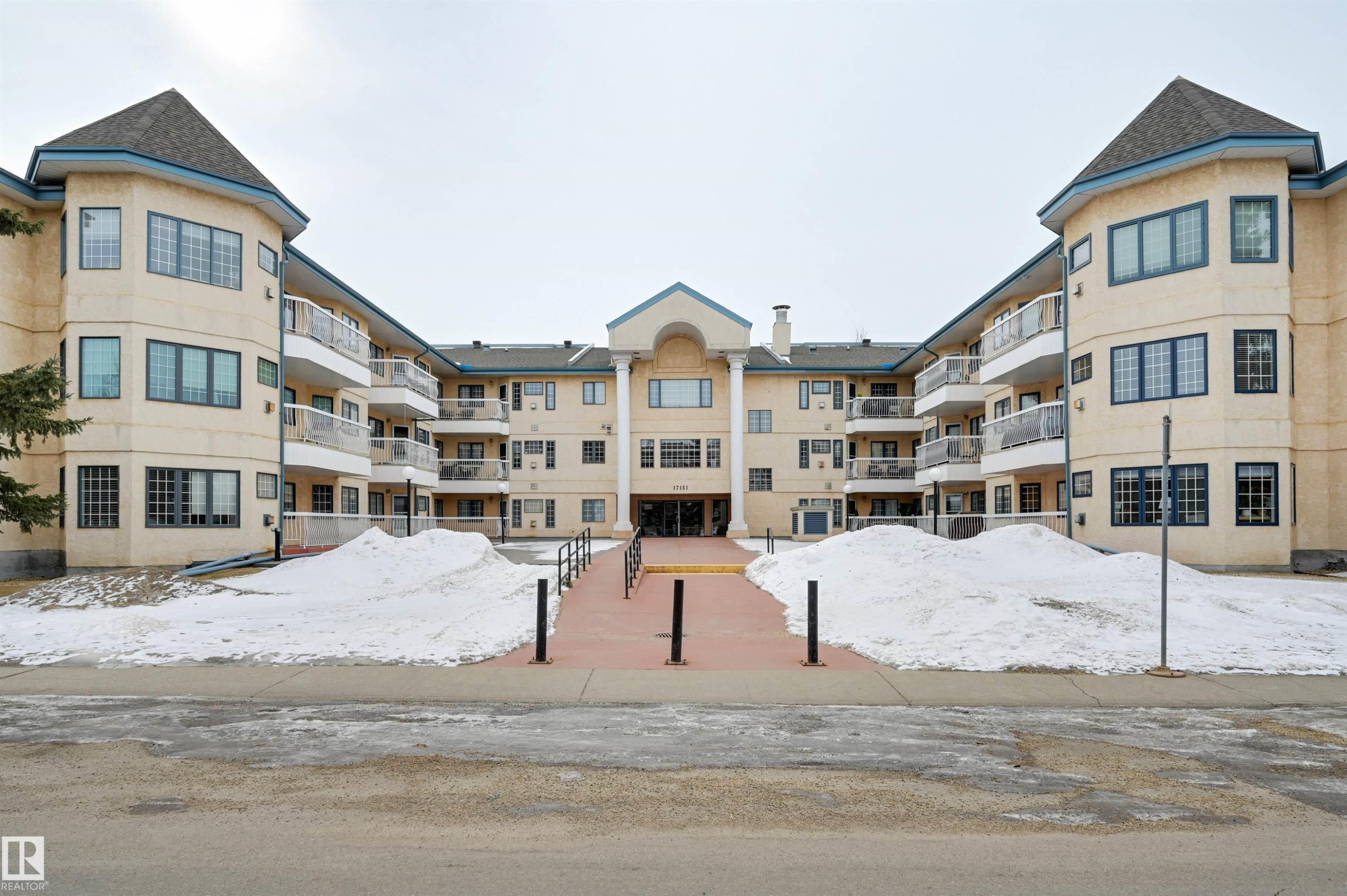 The property features a distinctive architectural design with a light-colored facade, numerous windows, and multiple balconies - 304 17151 94A Avenue, Edmonton, AB - Outdoor With Balcony With Facade