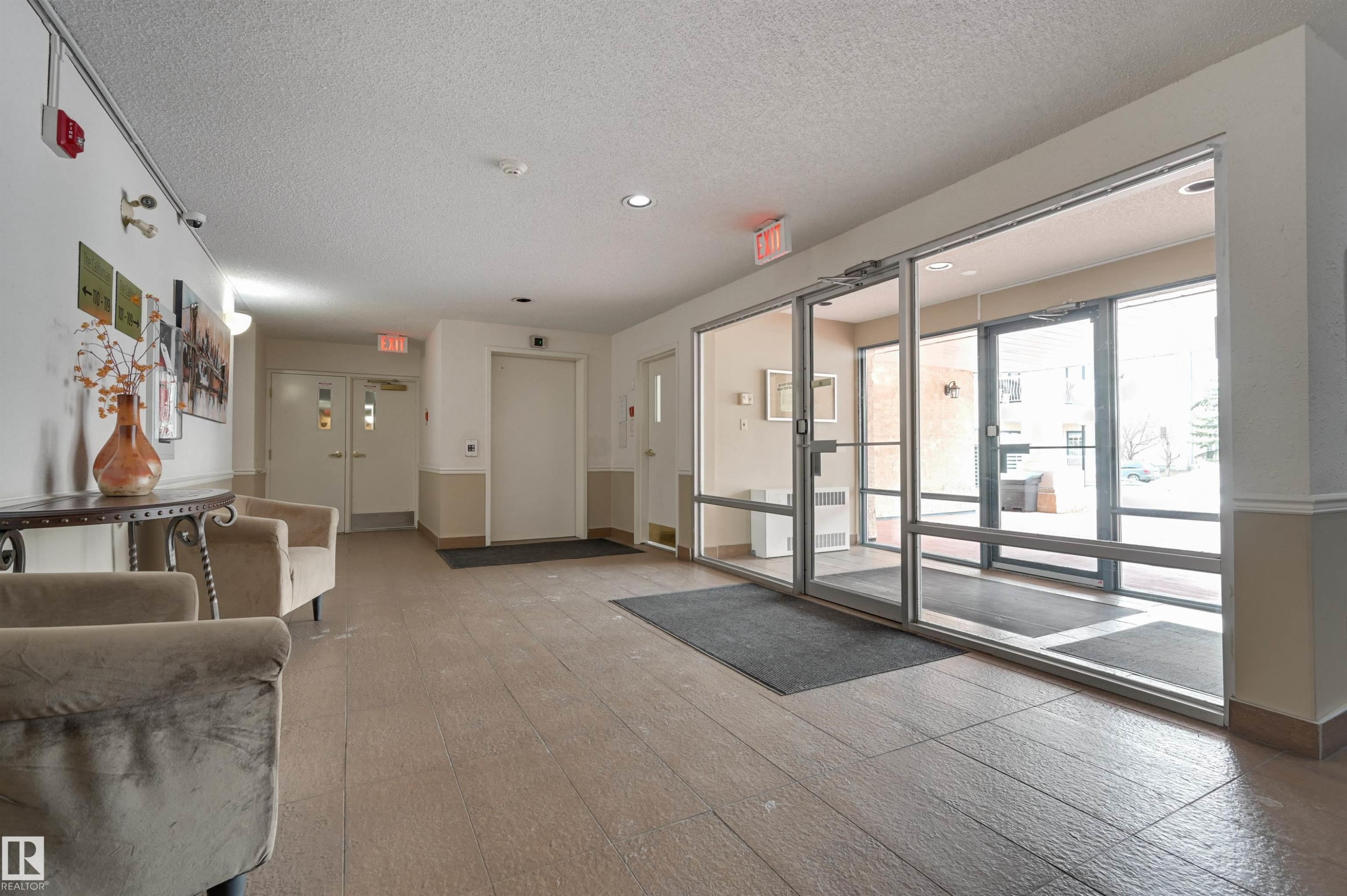 The property features a well-lit entrance area with large windows, providing natural light, and a tiled floor - 304 17151 94A Avenue, Edmonton, AB - Indoor Photo Showing Other Room