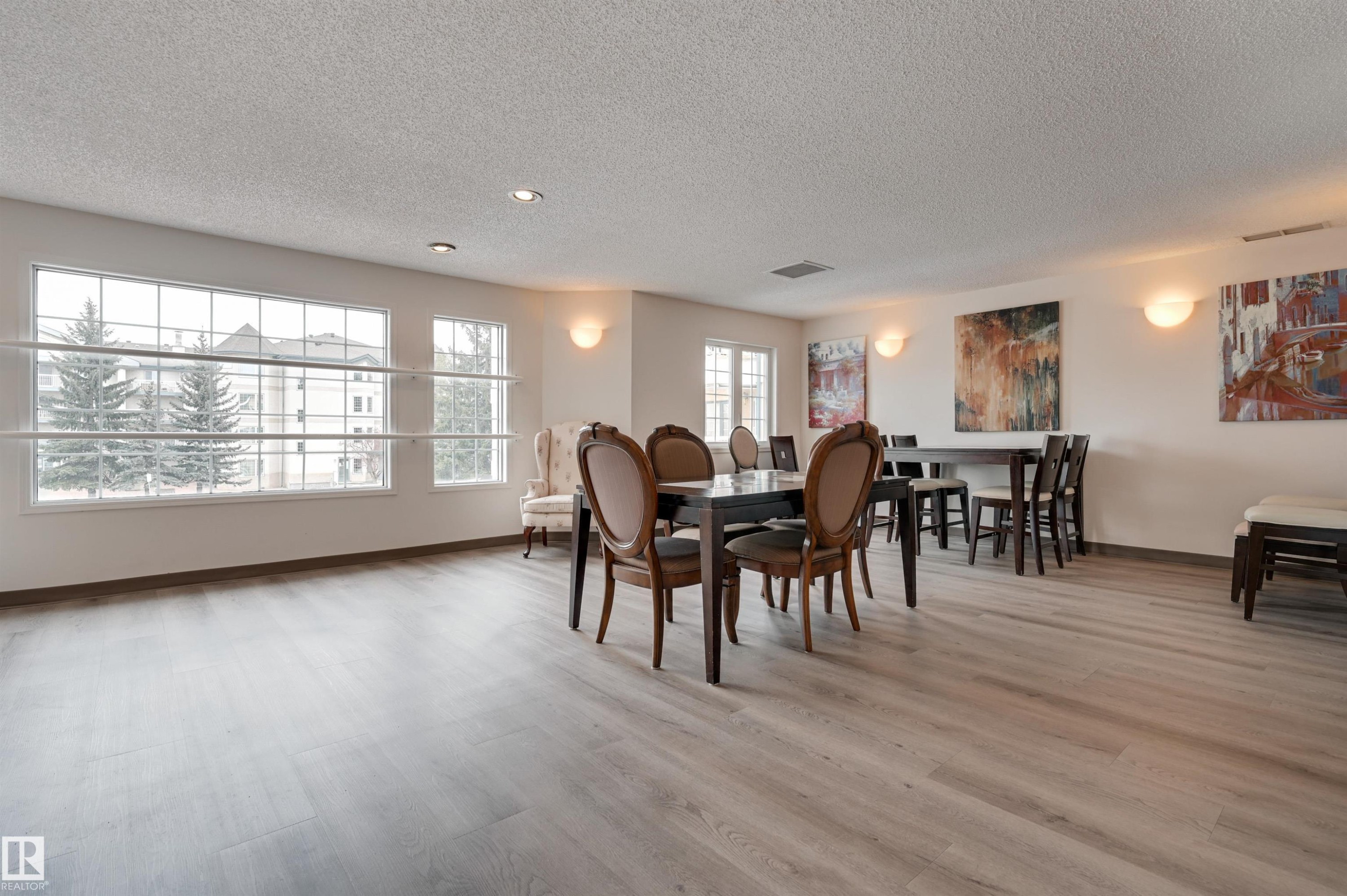 This spacious room features light-toned flooring, large windows providing natural light, and recessed lighting - 304 17151 94A Avenue, Edmonton, AB - Indoor Photo Showing Dining Room