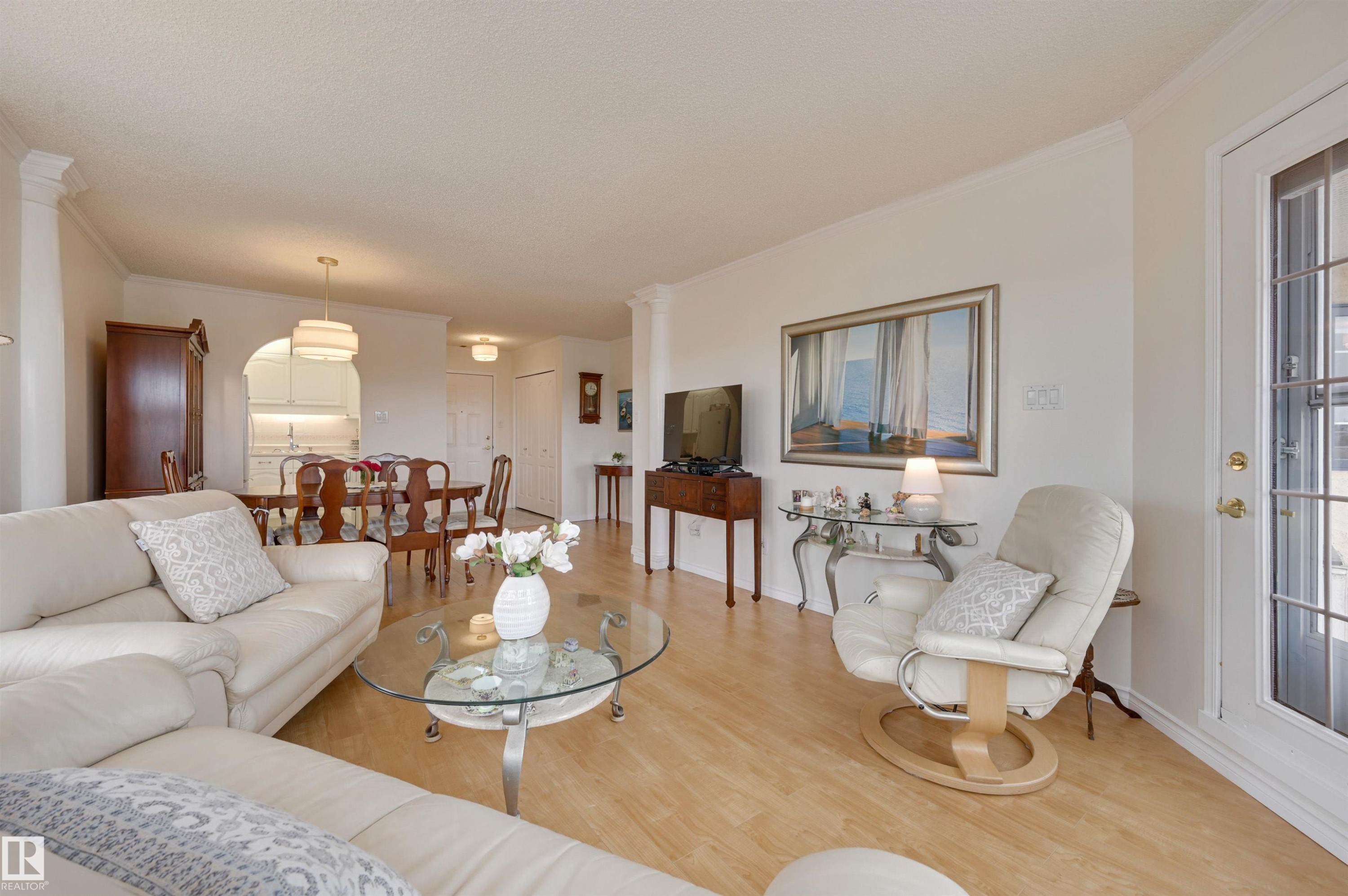 The living area features light-toned flooring, white walls, and crown molding - 304 17151 94A Avenue, Edmonton, AB - Indoor Photo Showing Living Room