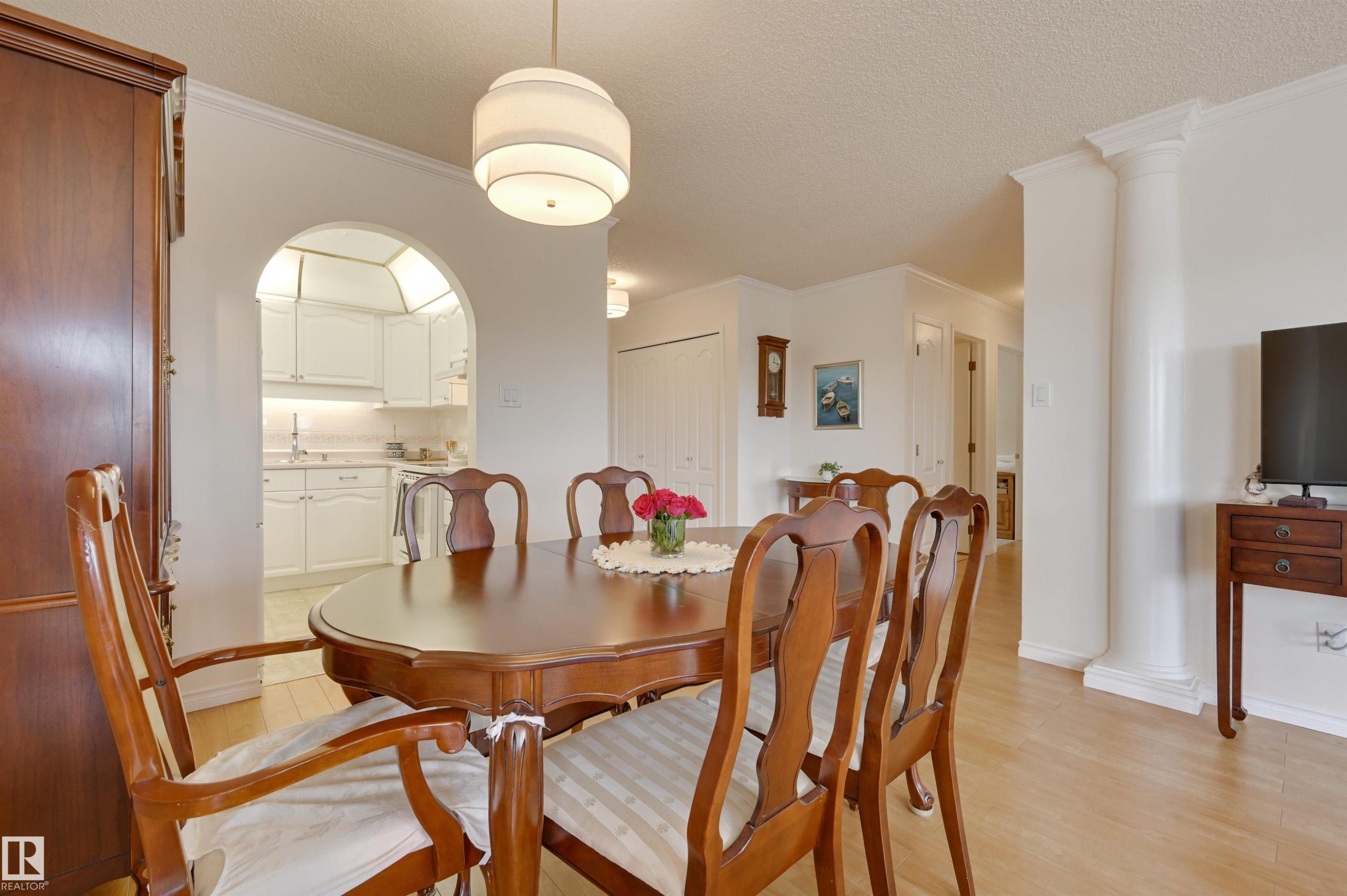 This dining area features hardwood flooring, an arched doorway, and a contemporary ceiling light fixture - 304 17151 94A Avenue, Edmonton, AB - Indoor Photo Showing Dining Room