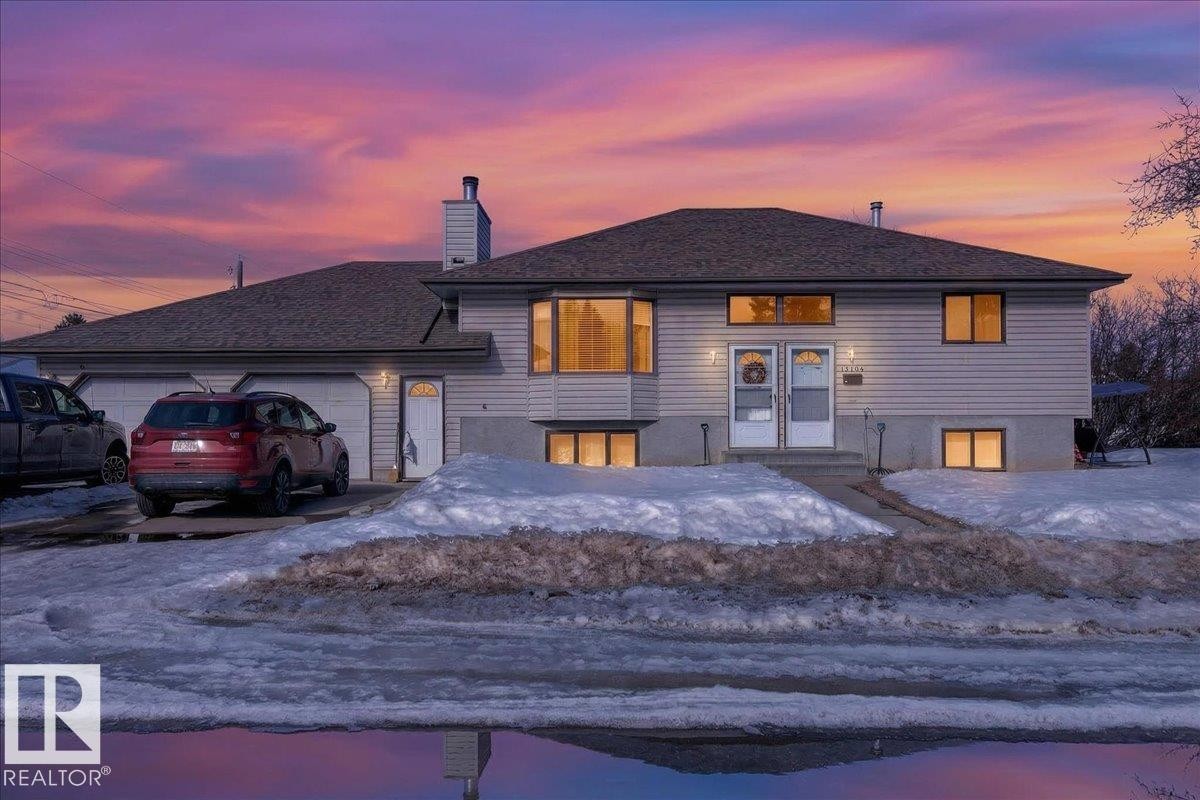 The property features a two-car garage, multiple windows providing natural light, and a sloped front yard - 13304 130 Avenue, Edmonton, AB - Outdoor