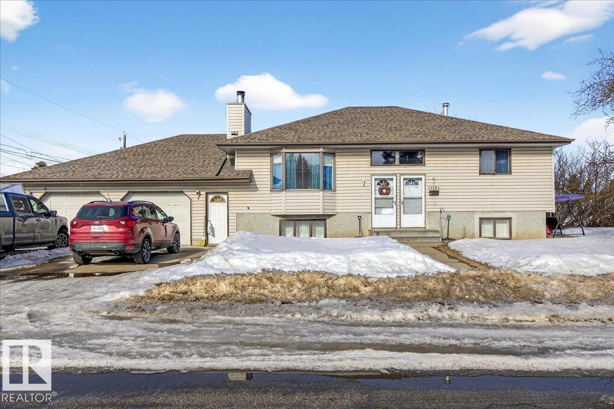 The property features a two-car garage with a paved driveway, and a light-colored siding exterior - 13304 130 Avenue, Edmonton, AB - Outdoor