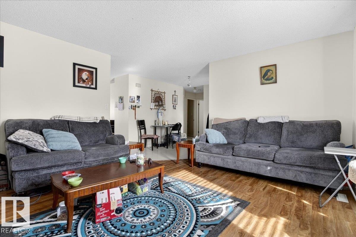 This living area features light-colored walls and wood-style flooring, offering a versatile foundation for various design preferences - 13304 130 Avenue, Edmonton, AB - Indoor Photo Showing Living Room