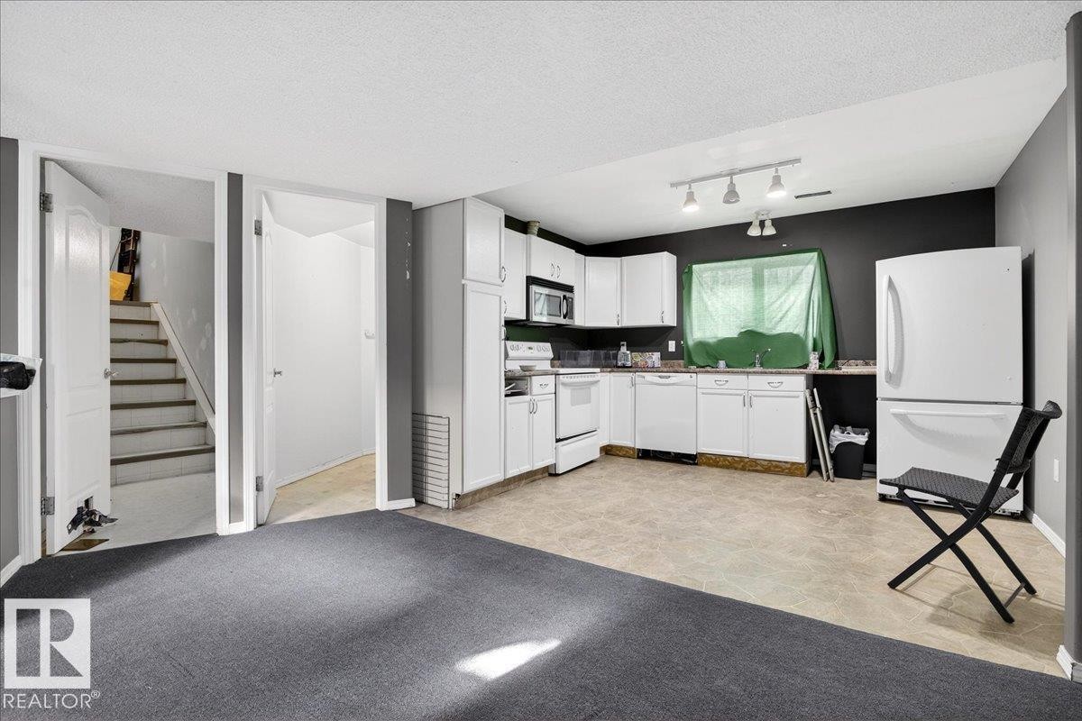 Well-appointed kitchen featuring white cabinetry, a white refrigerator, a white stove, and track lighting - 13304 130 Avenue, Edmonton, AB - Indoor Photo Showing Kitchen