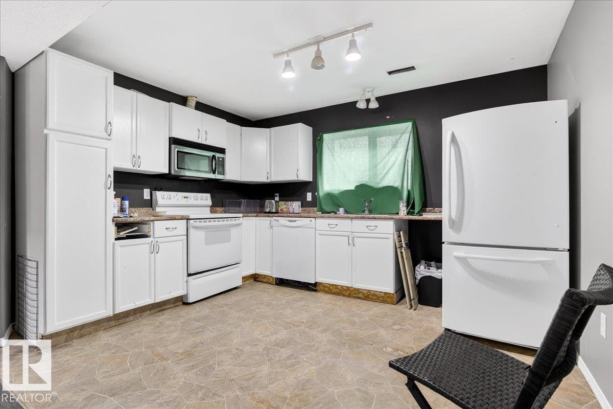 The kitchen features white cabinetry, a white refrigerator, and a white oven - 13304 130 Avenue, Edmonton, AB - Indoor Photo Showing Kitchen