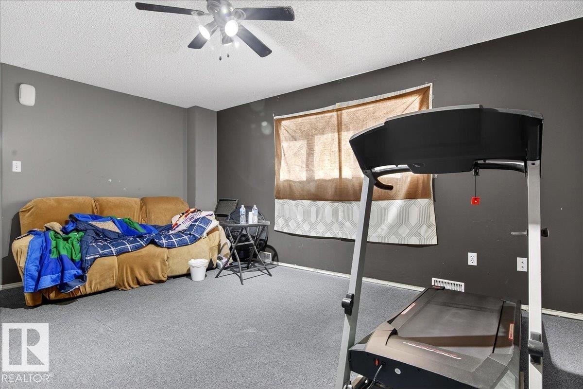 The room features a ceiling fan, dark grey walls, and light grey carpeting - 13304 130 Avenue, Edmonton, AB - Indoor Photo Showing Bedroom