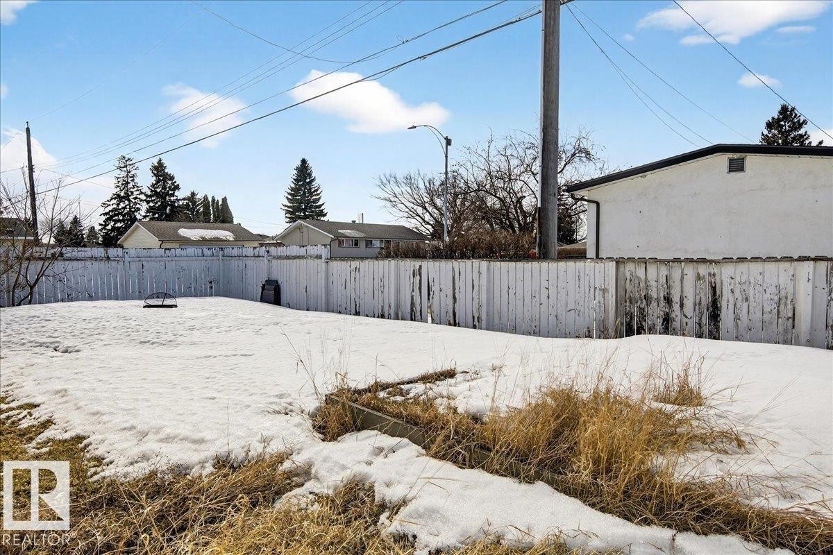 The property features a fenced yard with a snow-covered lawn - 13304 130 Avenue, Edmonton, AB - Outdoor