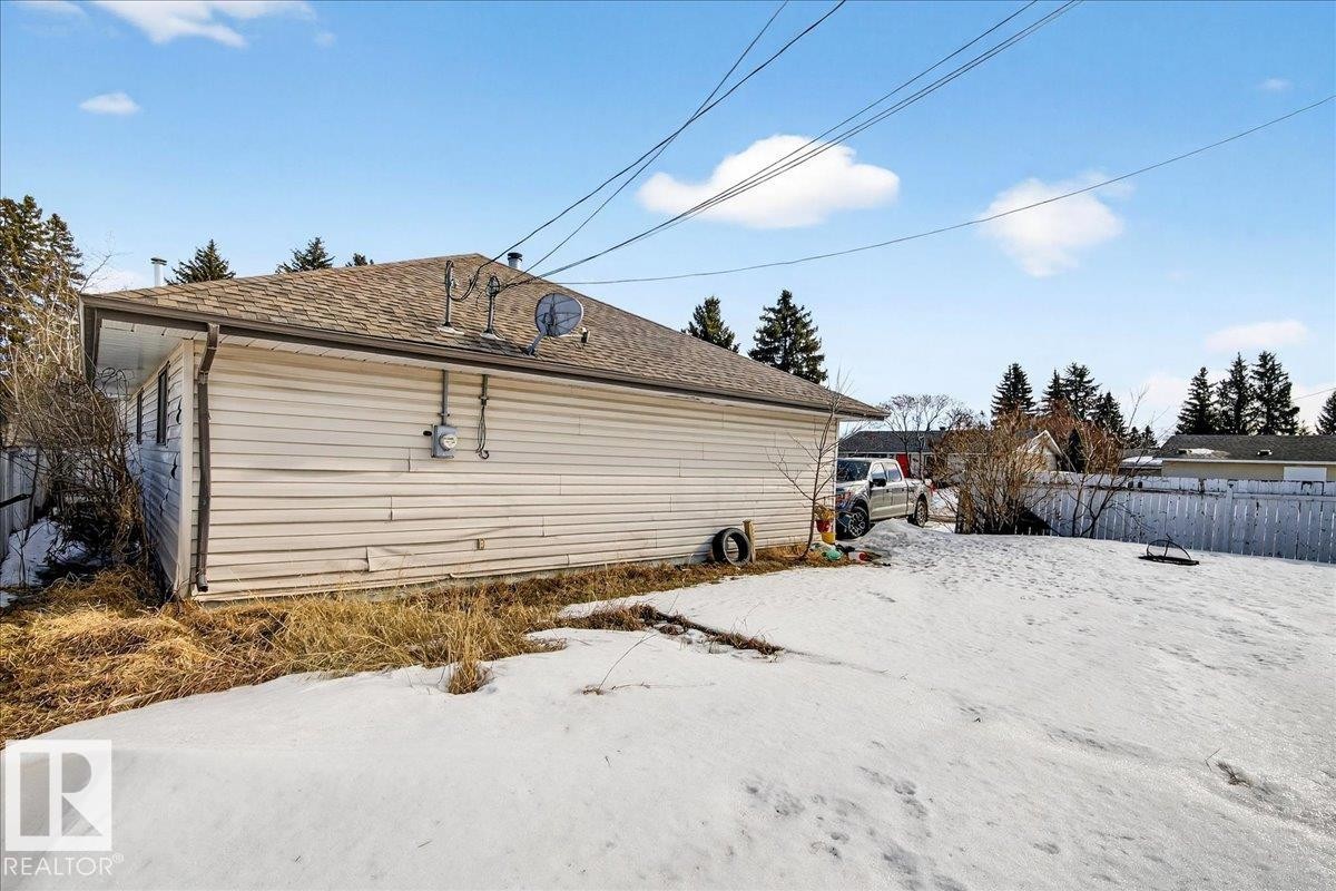 The property features a durable shingle roof, a light-colored siding exterior, and a spacious yard with a wooden fence - 13304 130 Avenue, Edmonton, AB - Outdoor With Exterior