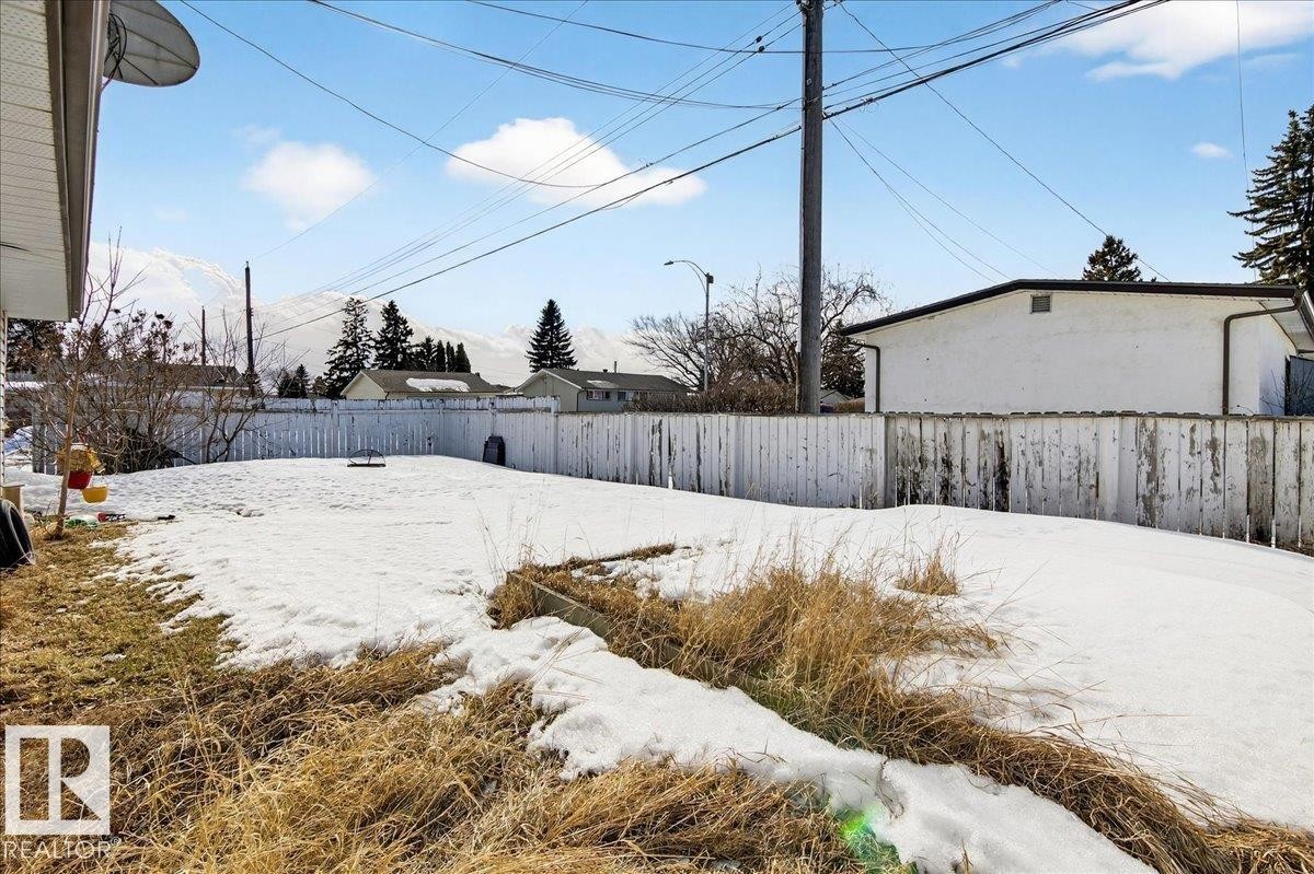 The property includes a spacious yard with a white picket fence, offering views of distant mountains - 13304 130 Avenue, Edmonton, AB - Outdoor