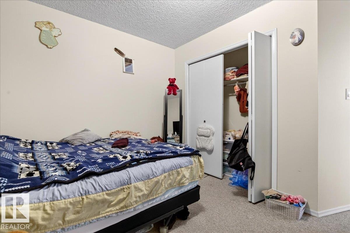 This room features neutral-toned walls, carpeted flooring, and a closet with bifold doors - 13304 130 Avenue, Edmonton, AB - Indoor Photo Showing Bedroom