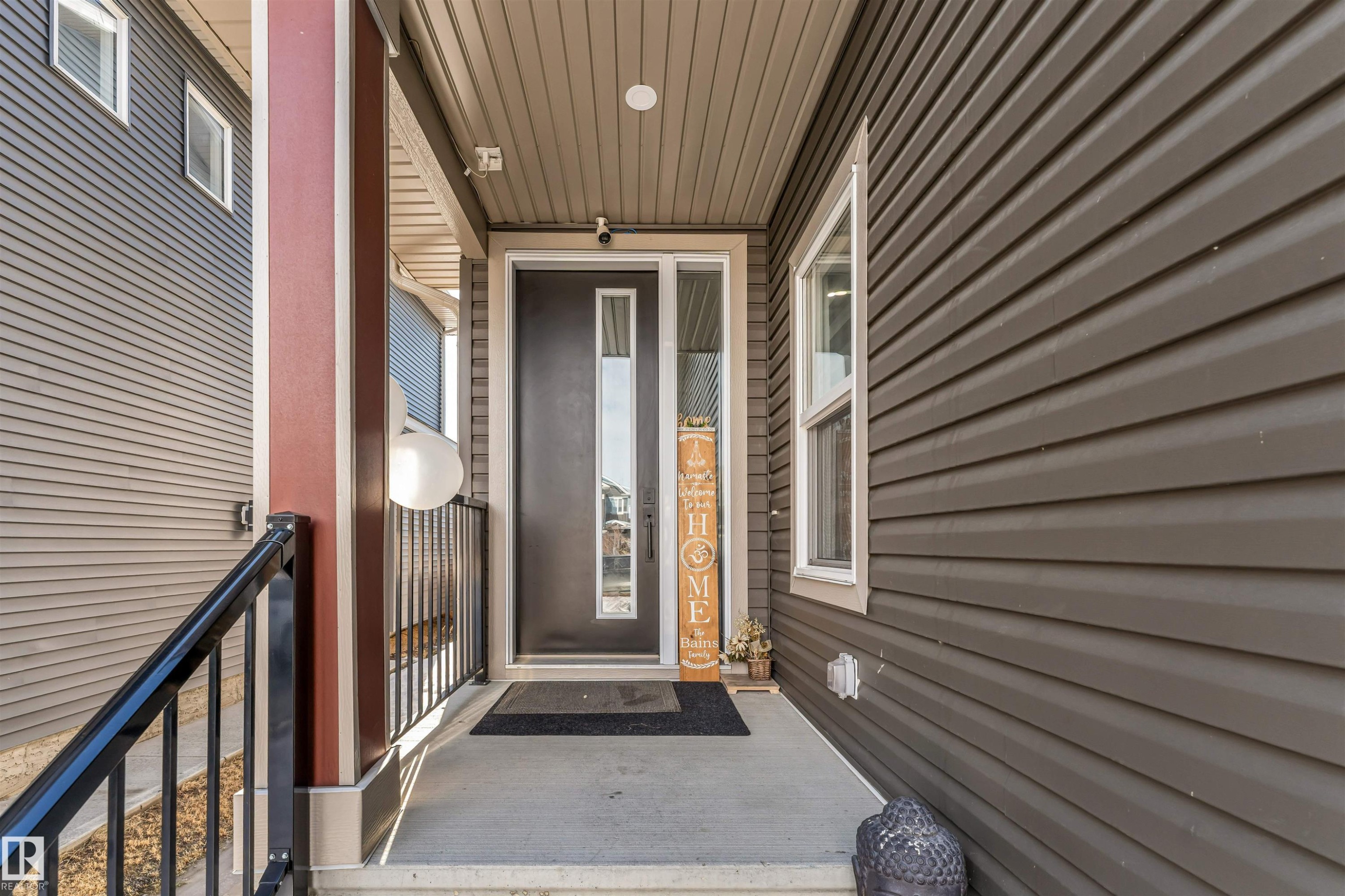 Inviting front entry featuring a covered porch, a dark entry door with a vertical glass insert, and durable siding in a neutral tone - 1531 151 Avenue, Edmonton, AB - Outdoor With Exterior