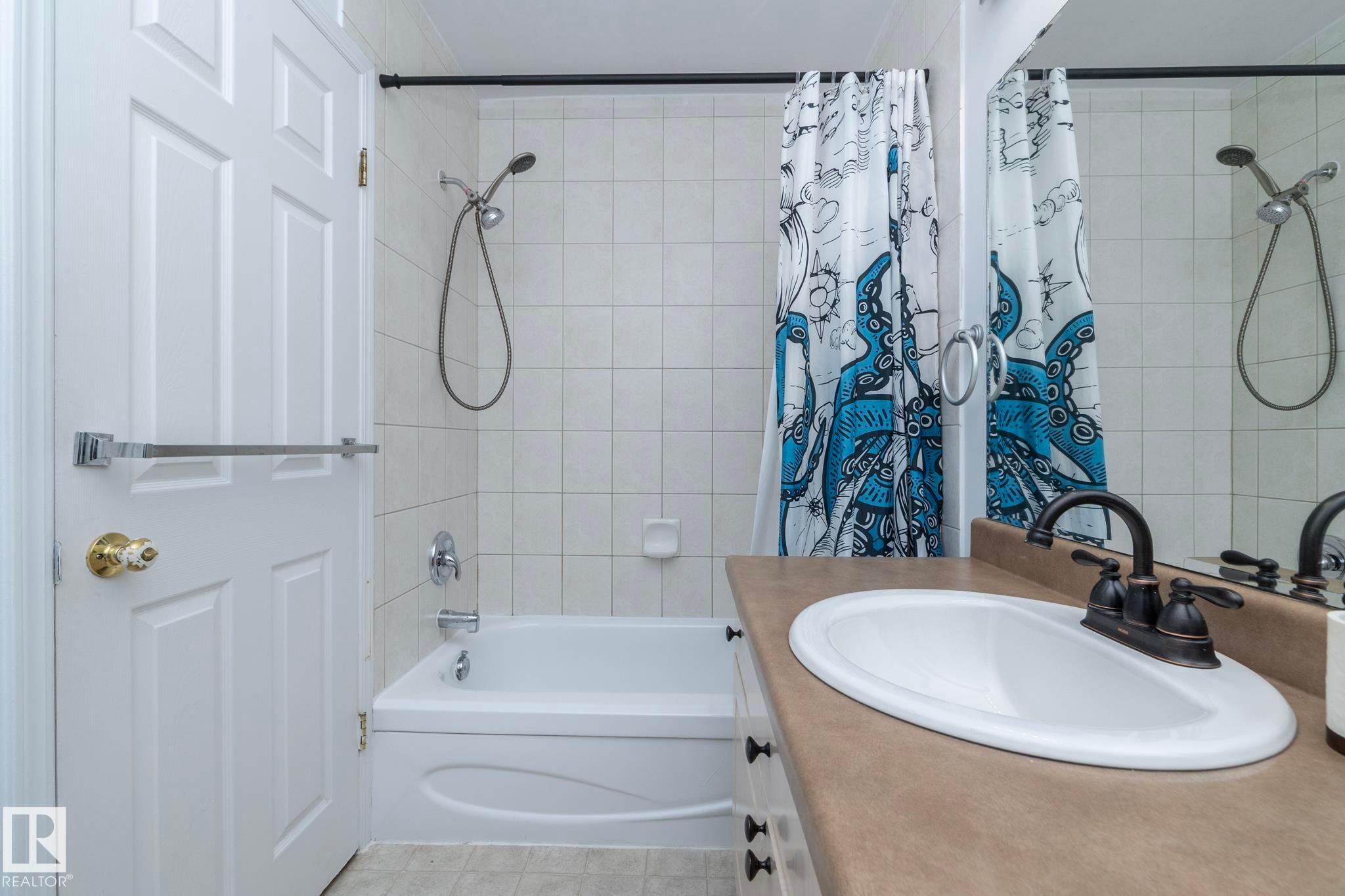 The bathroom features a bathtub with a shower, a tiled shower surround, and a vanity with an integrated sink and a dark-toned faucet - 6 Glaewyn Estates, St. Albert, AB - Indoor Photo Showing Bathroom