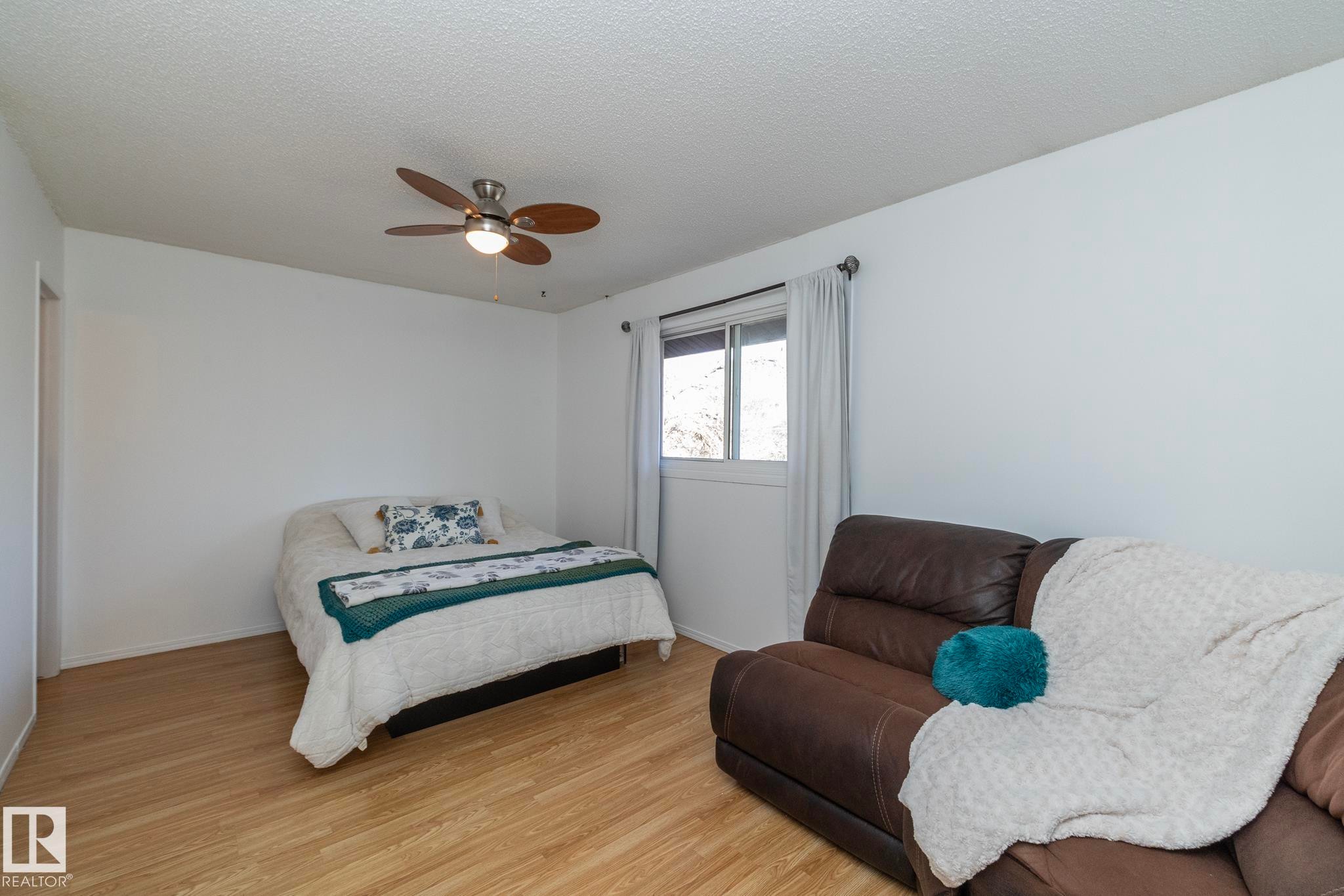 Room featuring light wood-look flooring, white walls, and a ceiling fan with light - 6 Glaewyn Estates, St. Albert, AB - Indoor Photo Showing Bedroom