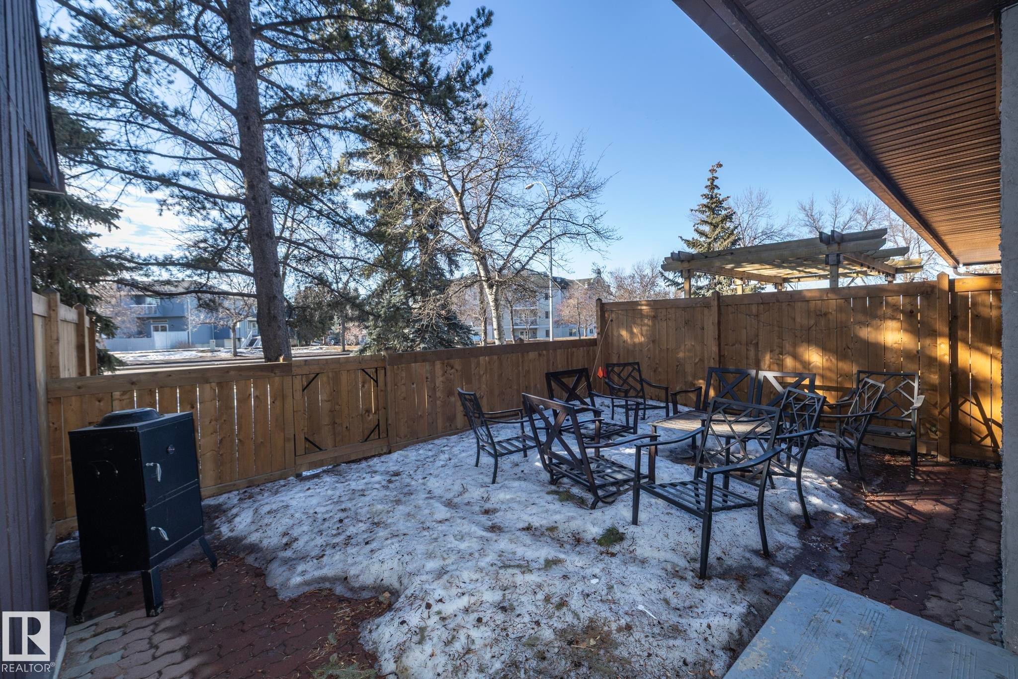 The property features an outdoor patio area with brick paving, a wooden fence, and mature trees visible beyond the fence - 6 Glaewyn Estates, St. Albert, AB - Outdoor With Deck Patio Veranda