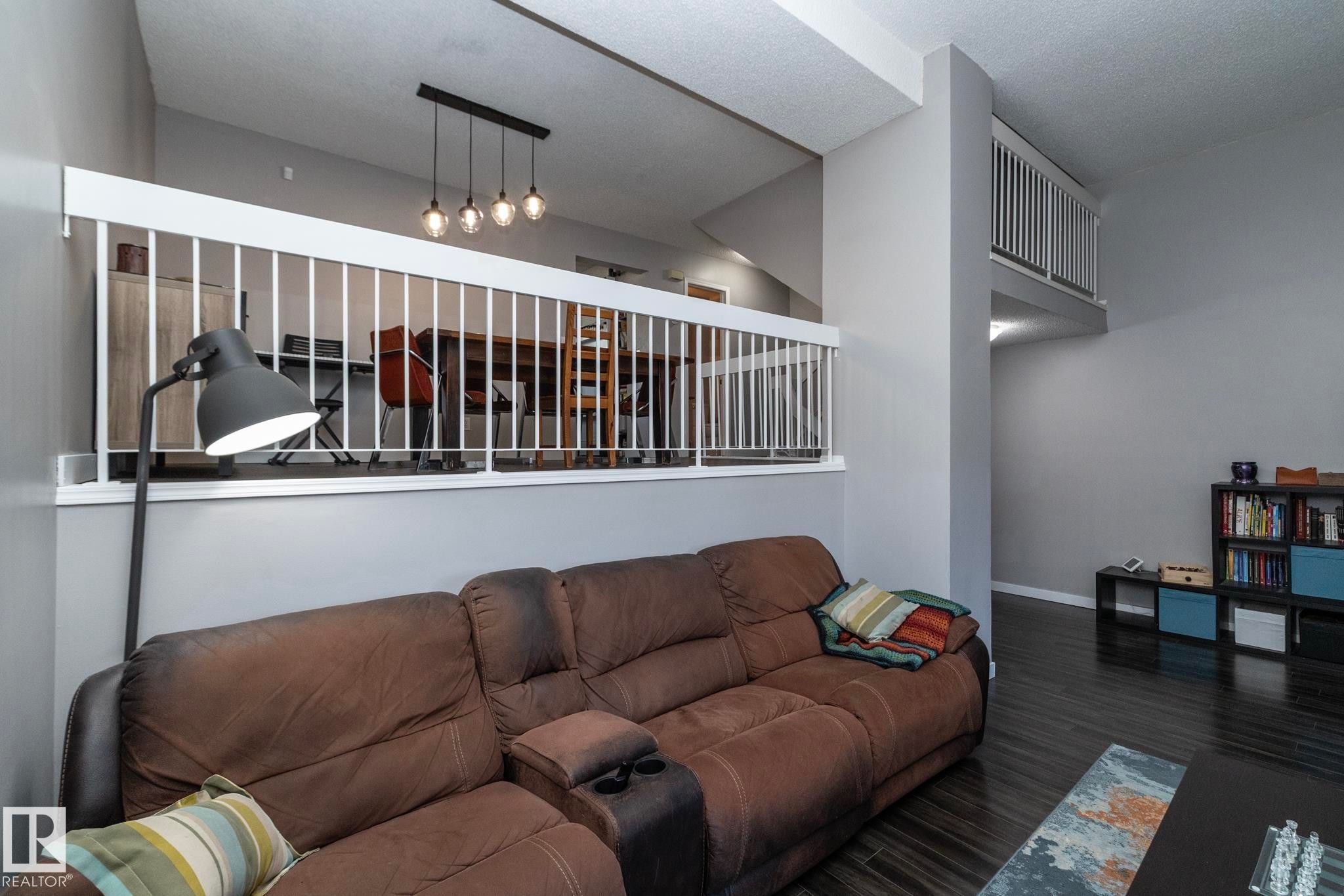 The property features a spacious living area with dark wood flooring and a white railing overlooking an additional area - 6 Glaewyn Estates, St. Albert, AB - Indoor Photo Showing Living Room