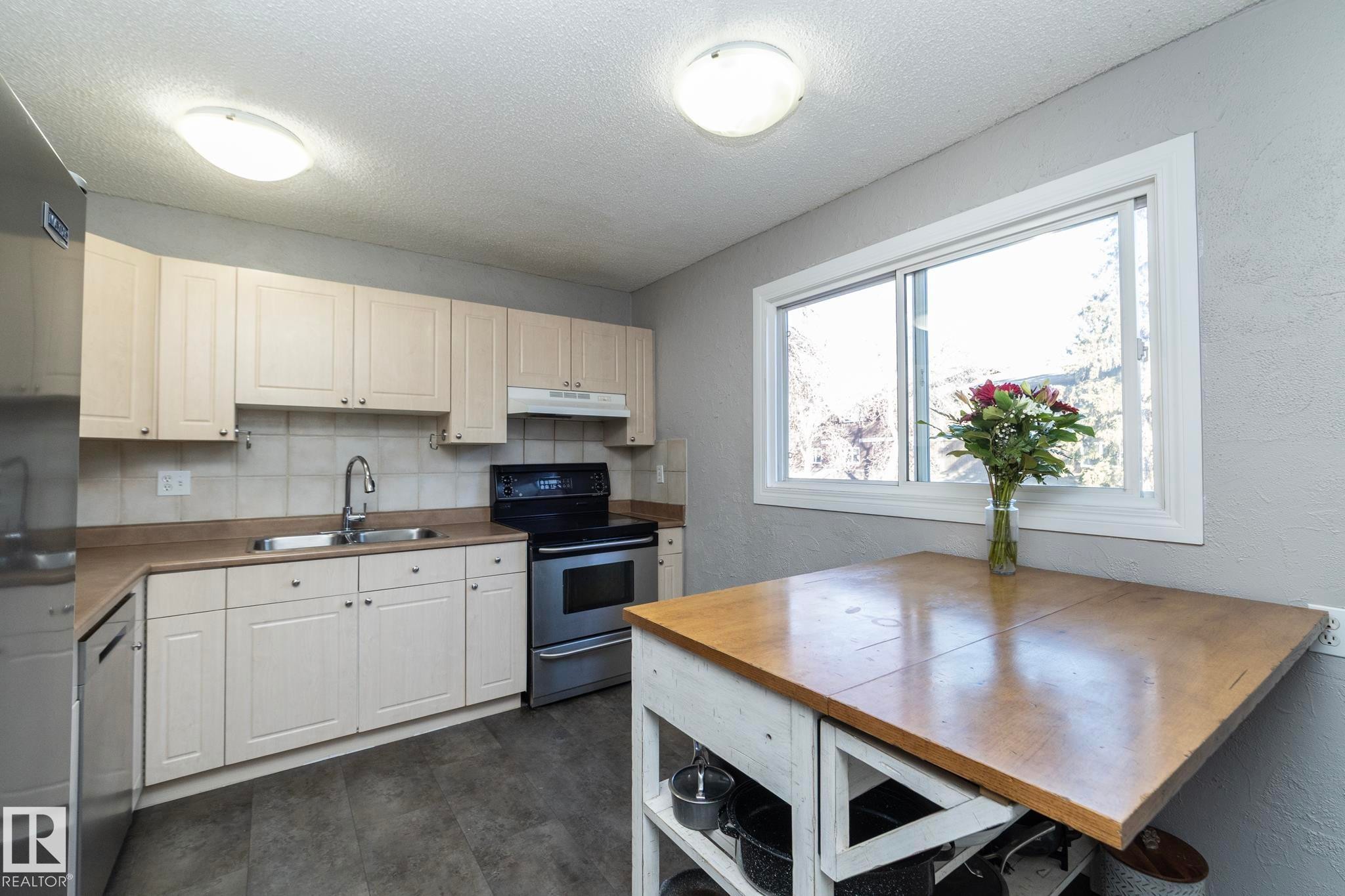 Kitchen featuring light-toned cabinetry, stainless steel appliances, a window providing natural light, and a wooden-topped island - 6 Glaewyn Estates, St. Albert, AB - Indoor Photo Showing Kitchen With Double Sink