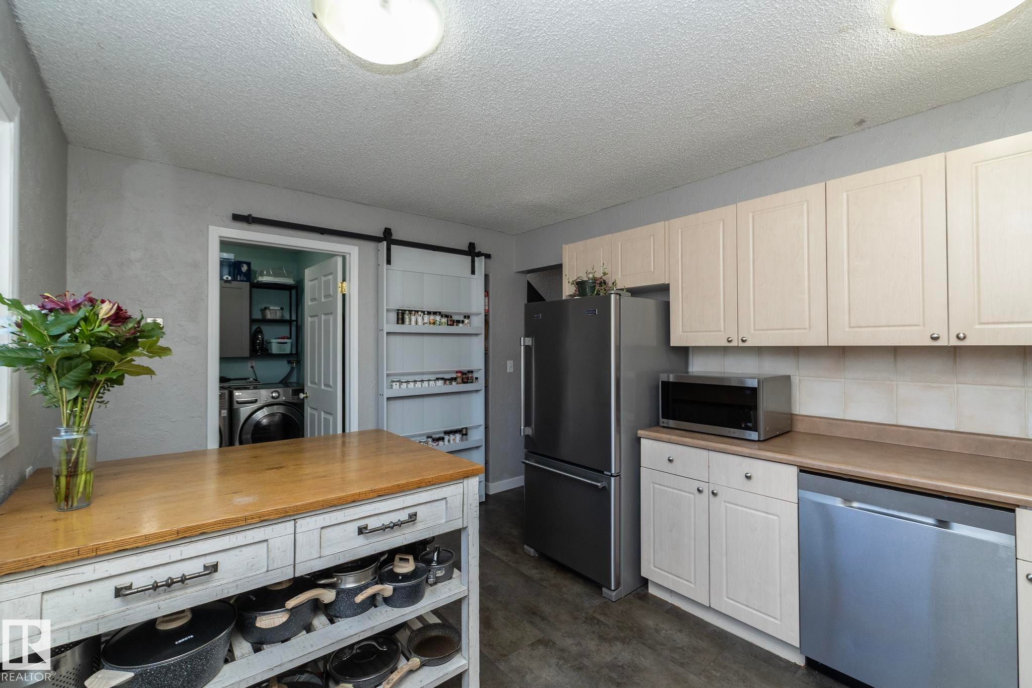 The kitchen features light-colored cabinetry, a stainless steel refrigerator, and a dishwasher - 6 Glaewyn Estates, St. Albert, AB - Indoor Photo Showing Kitchen