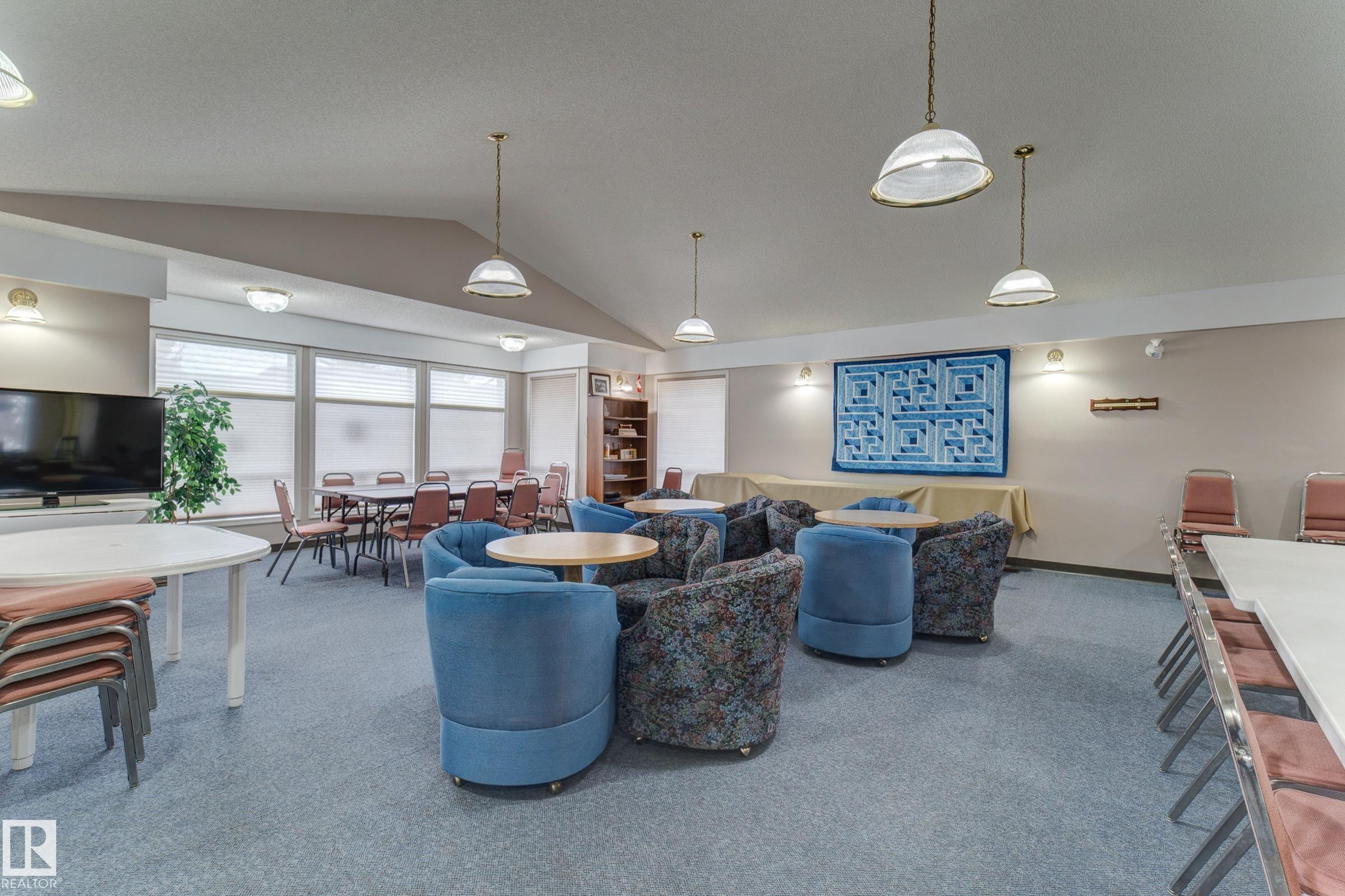 Spacious common area featuring vaulted ceilings, a variety of seating arrangements, and large windows with blinds - 5 308 Jackson Road, Edmonton, AB - Indoor