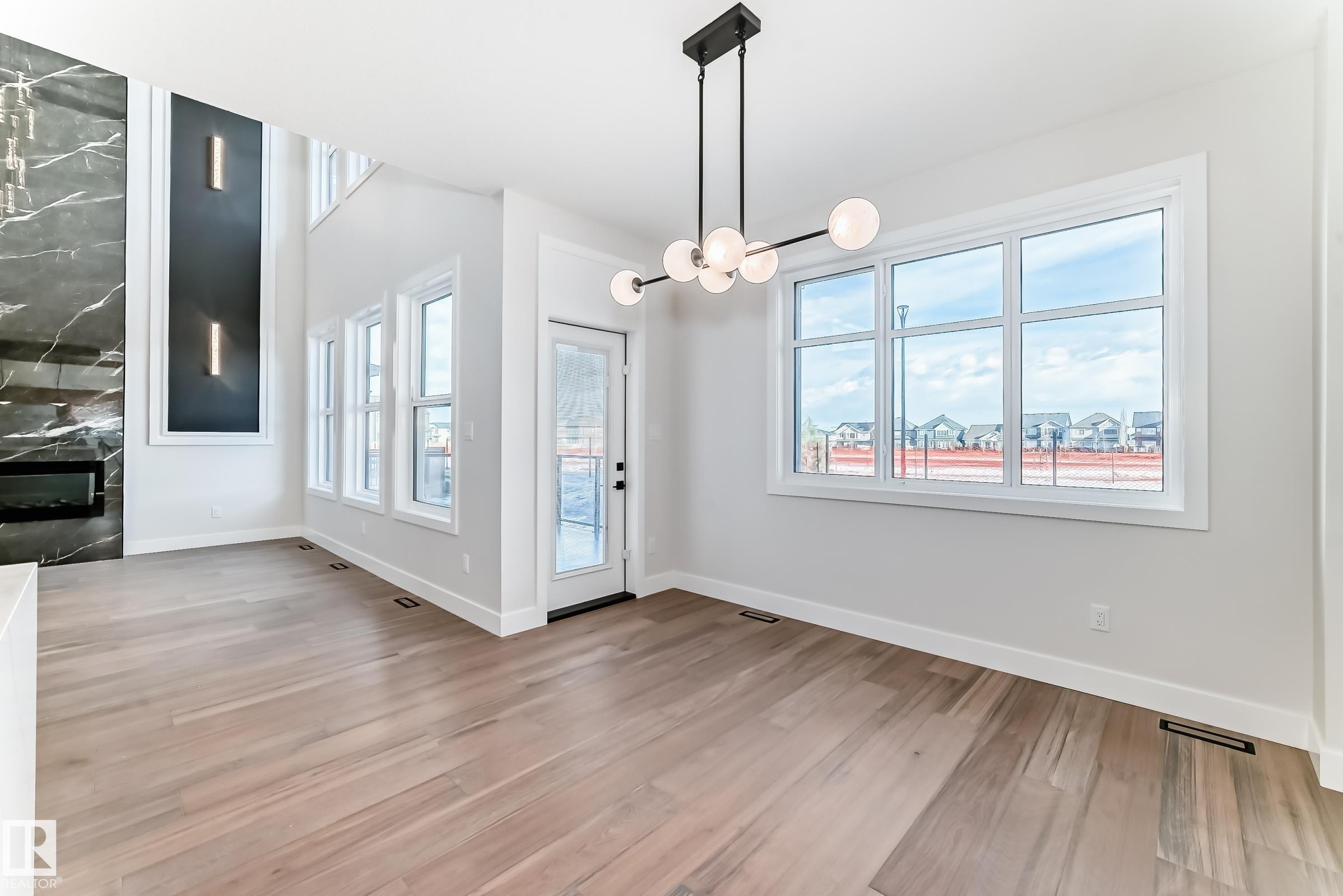 This open-concept interior features light-toned hardwood flooring throughout - 7665 Kimiwan Crescent, Edmonton, AB - Indoor Photo Showing Other Room