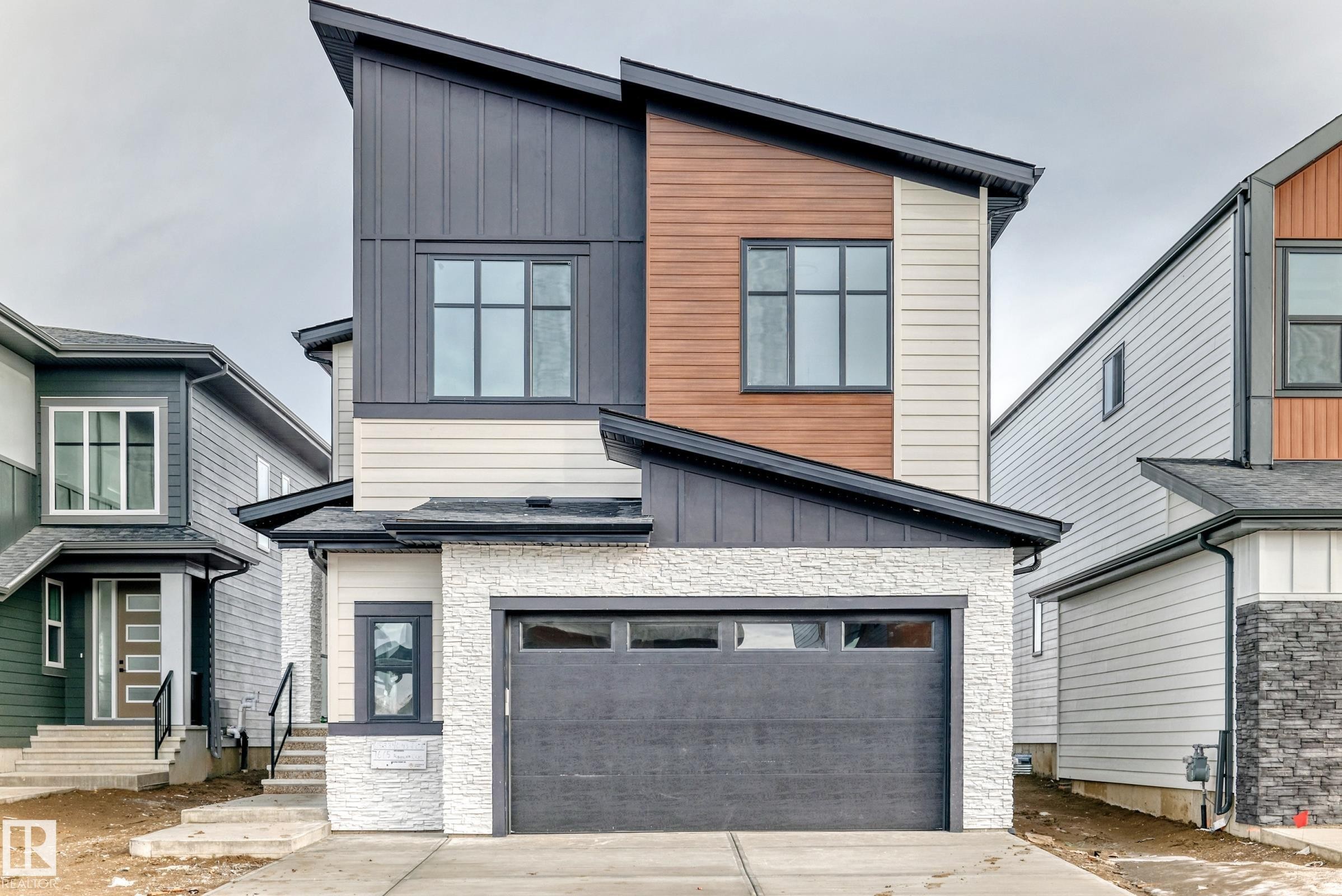 Modern property with a two-car garage, multi-pane windows, and a distinctive sloped roofline - 7665 Kimiwan Crescent, Edmonton, AB - Outdoor