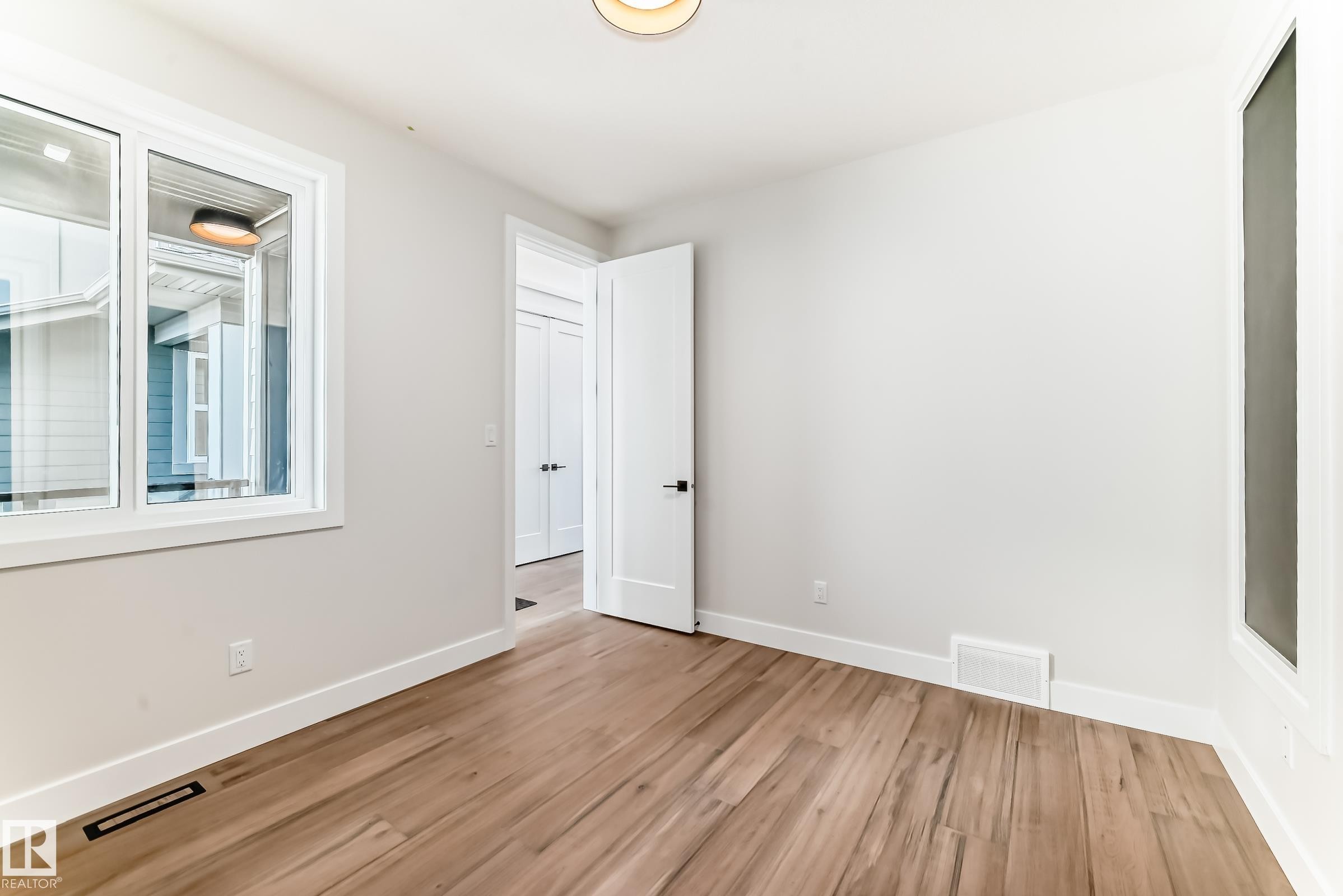 This room features hardwood flooring, white walls, and a window with white trim - 7665 Kimiwan Crescent, Edmonton, AB - Indoor Photo Showing Other Room