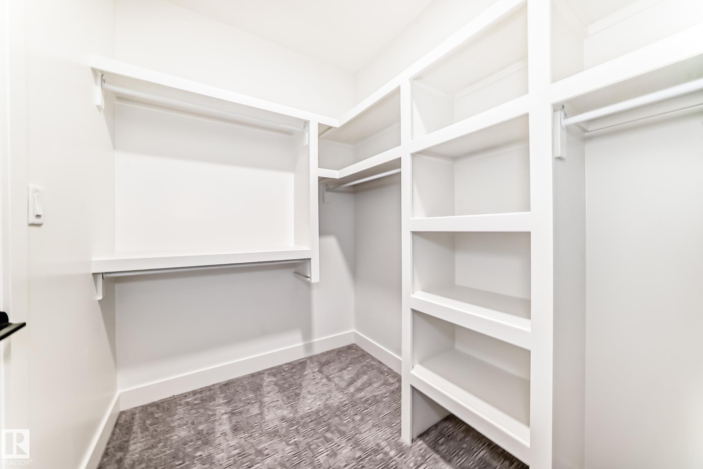 Walk-in closet featuring built-in shelving, hanging rods, and patterned carpeting - 7665 Kimiwan Crescent, Edmonton, AB - Indoor With Storage