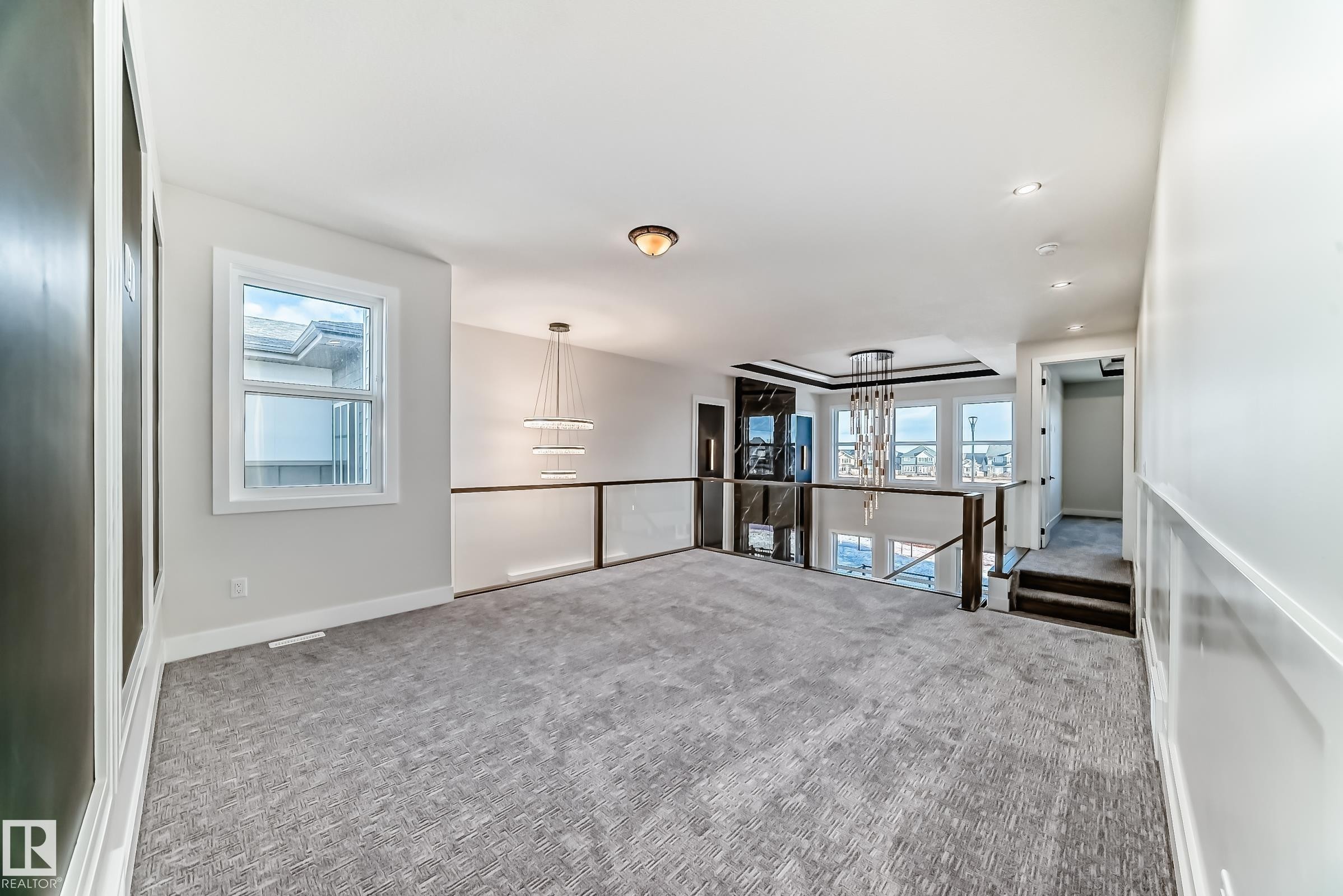 Spacious room featuring carpeting, a window, and a modern chandelier - 7665 Kimiwan Crescent, Edmonton, AB - Indoor Photo Showing Other Room