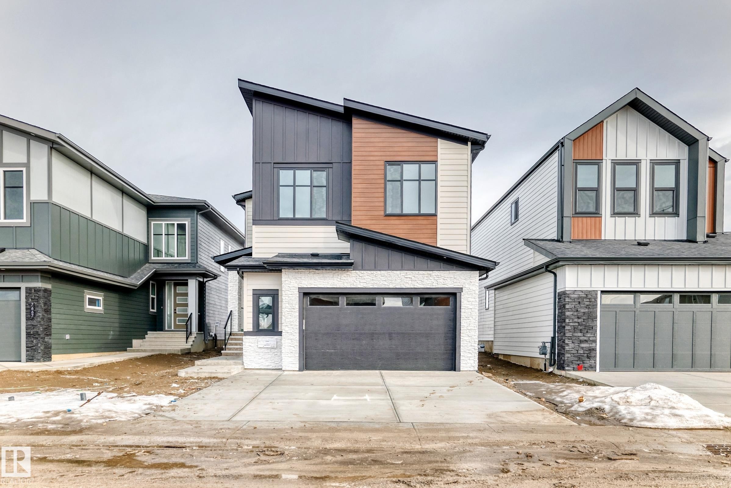 This property features modern architectural design with a distinctive angled roofline and multi-toned siding, including dark paneling, light siding, and warm wood-toned accents - 7665 Kimiwan Crescent, Edmonton, AB - Outdoor With Facade